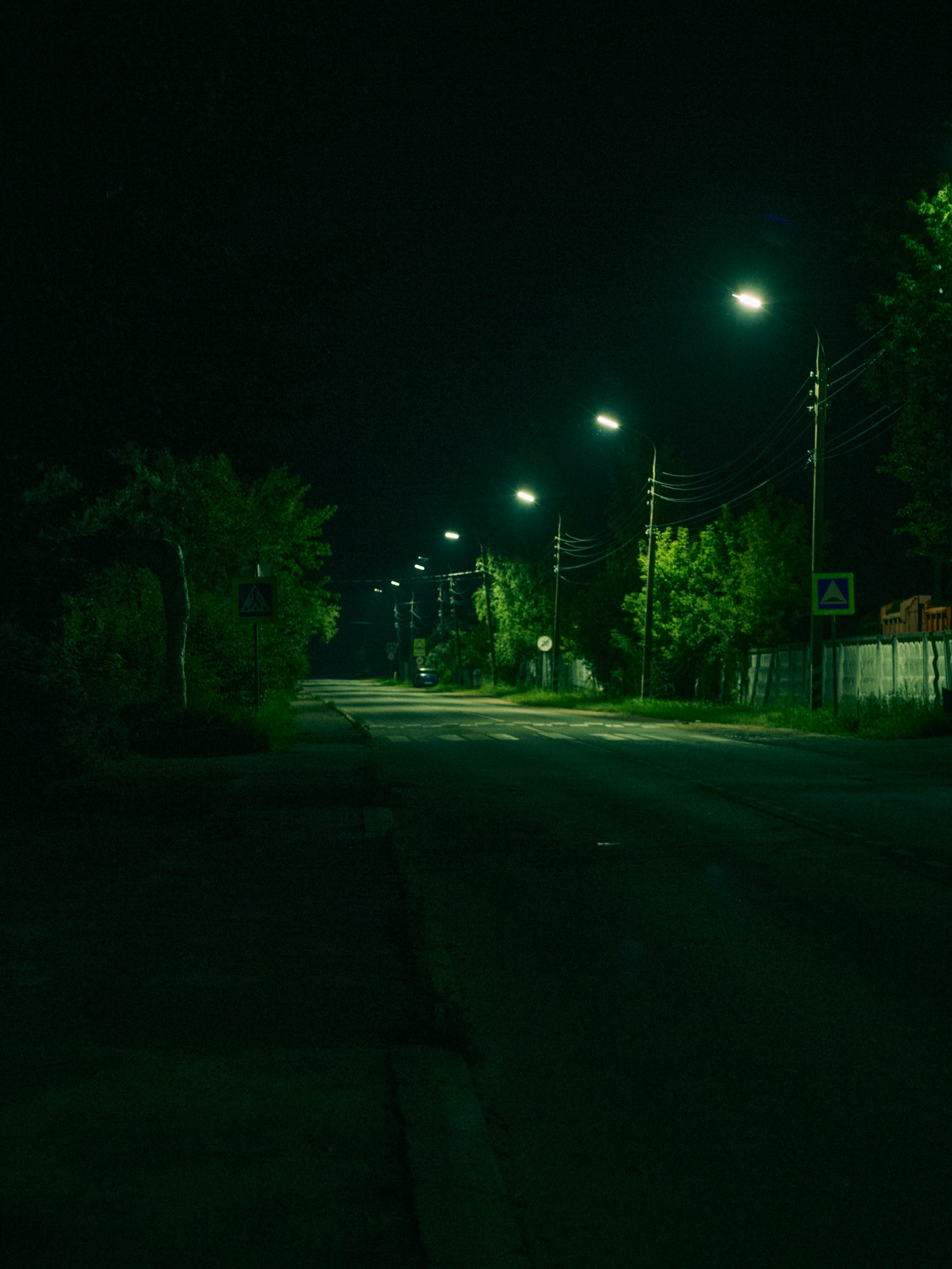 A quiet road at night illuminated by a row of bright streetlights