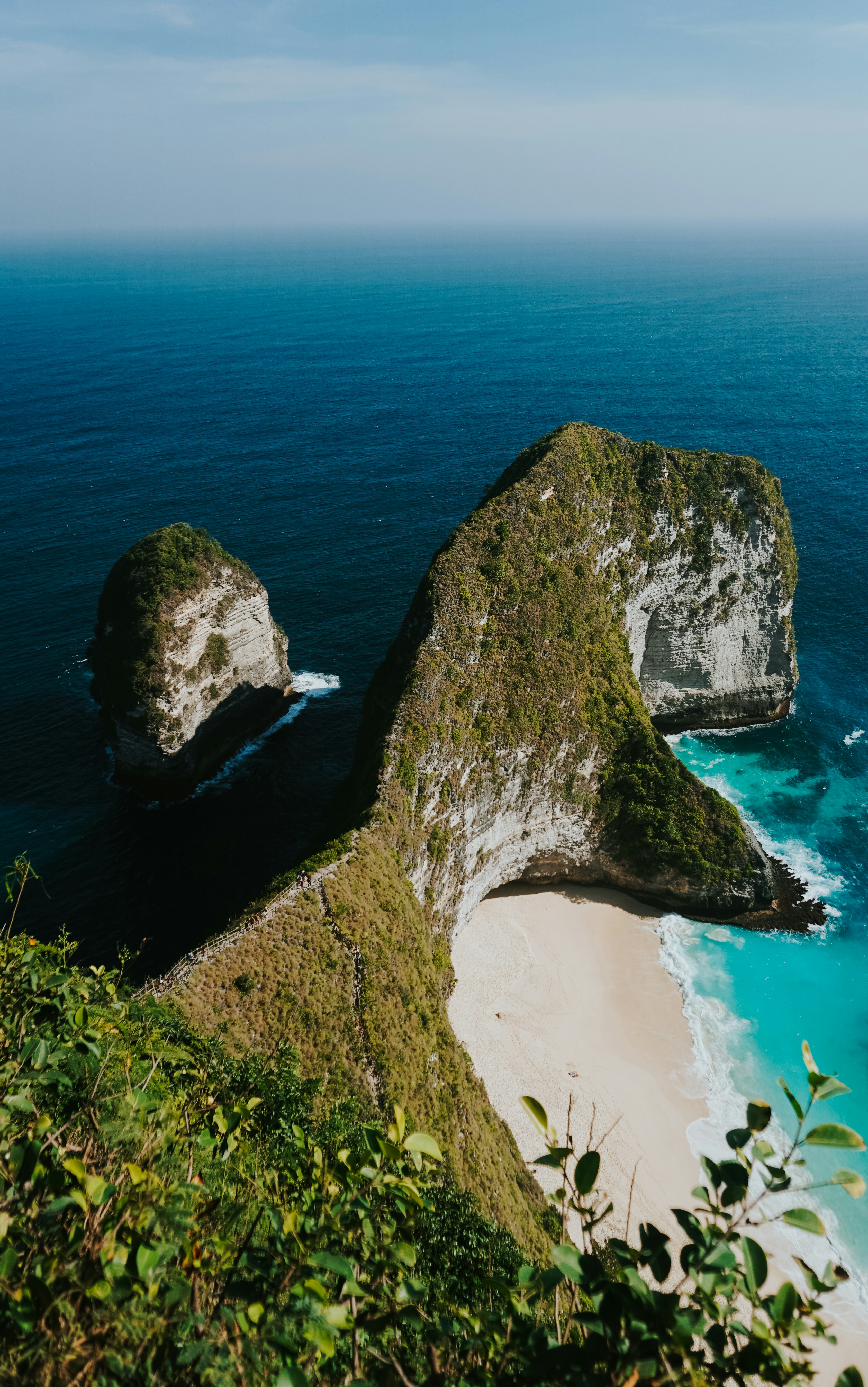 A high cliff formation above a white sand beach and turquoise ocean water