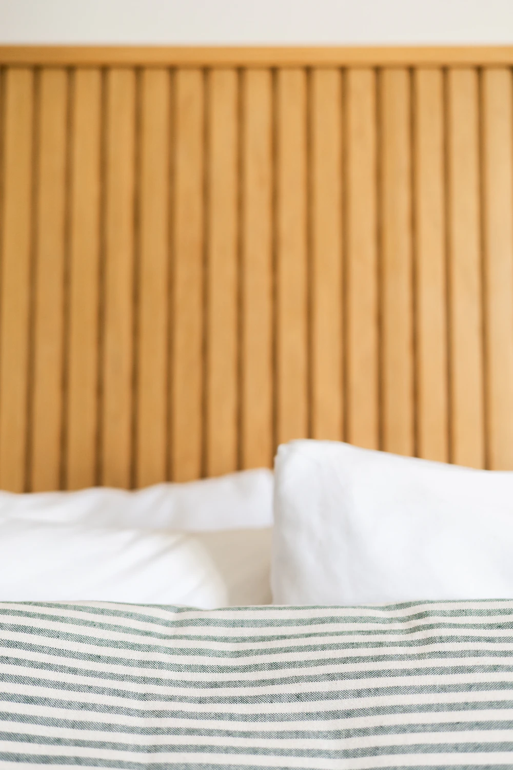Soft white pillows against a slatted oak headboard