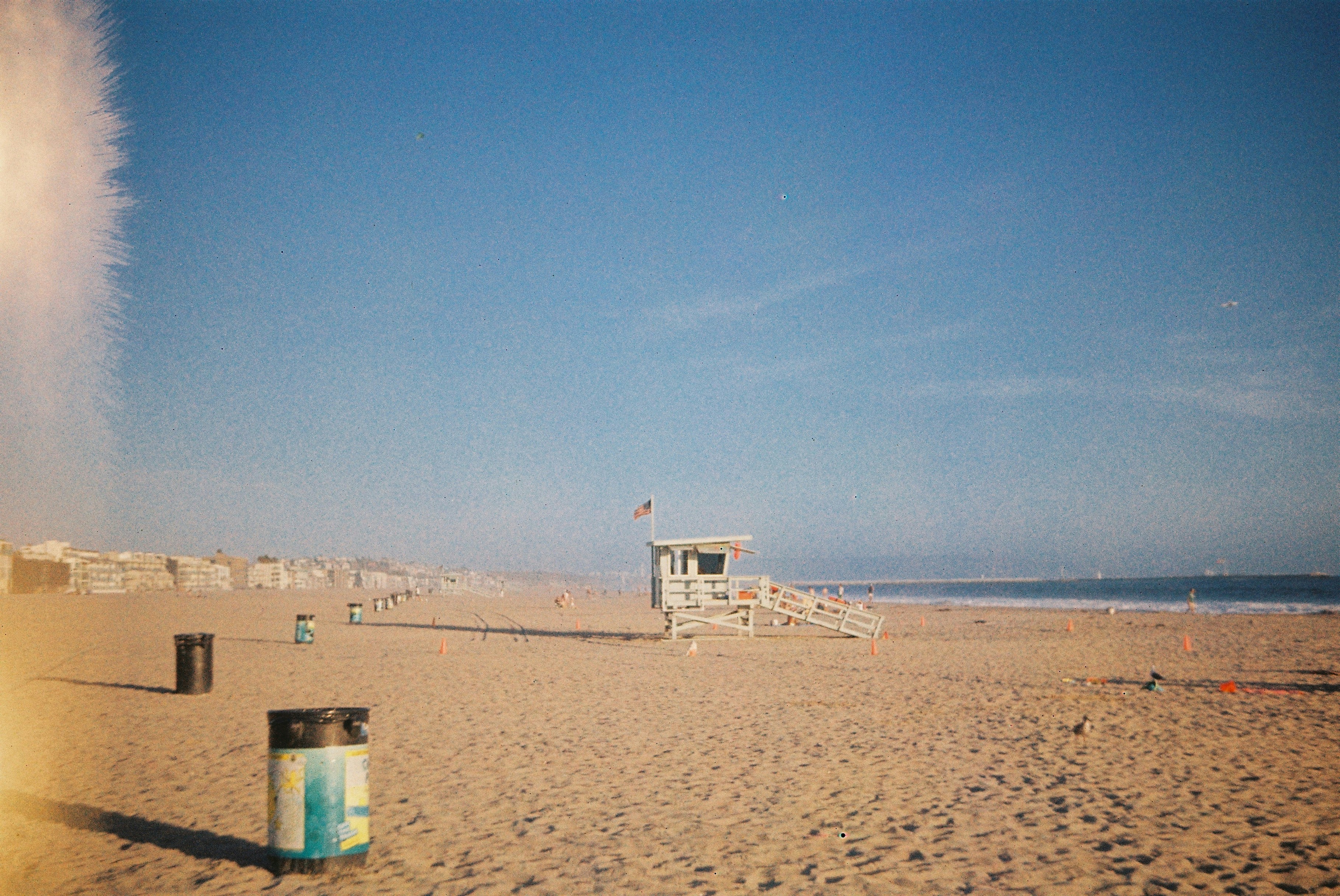 A wooden lifeguard tower on a sandy beach under a clear blue sky.