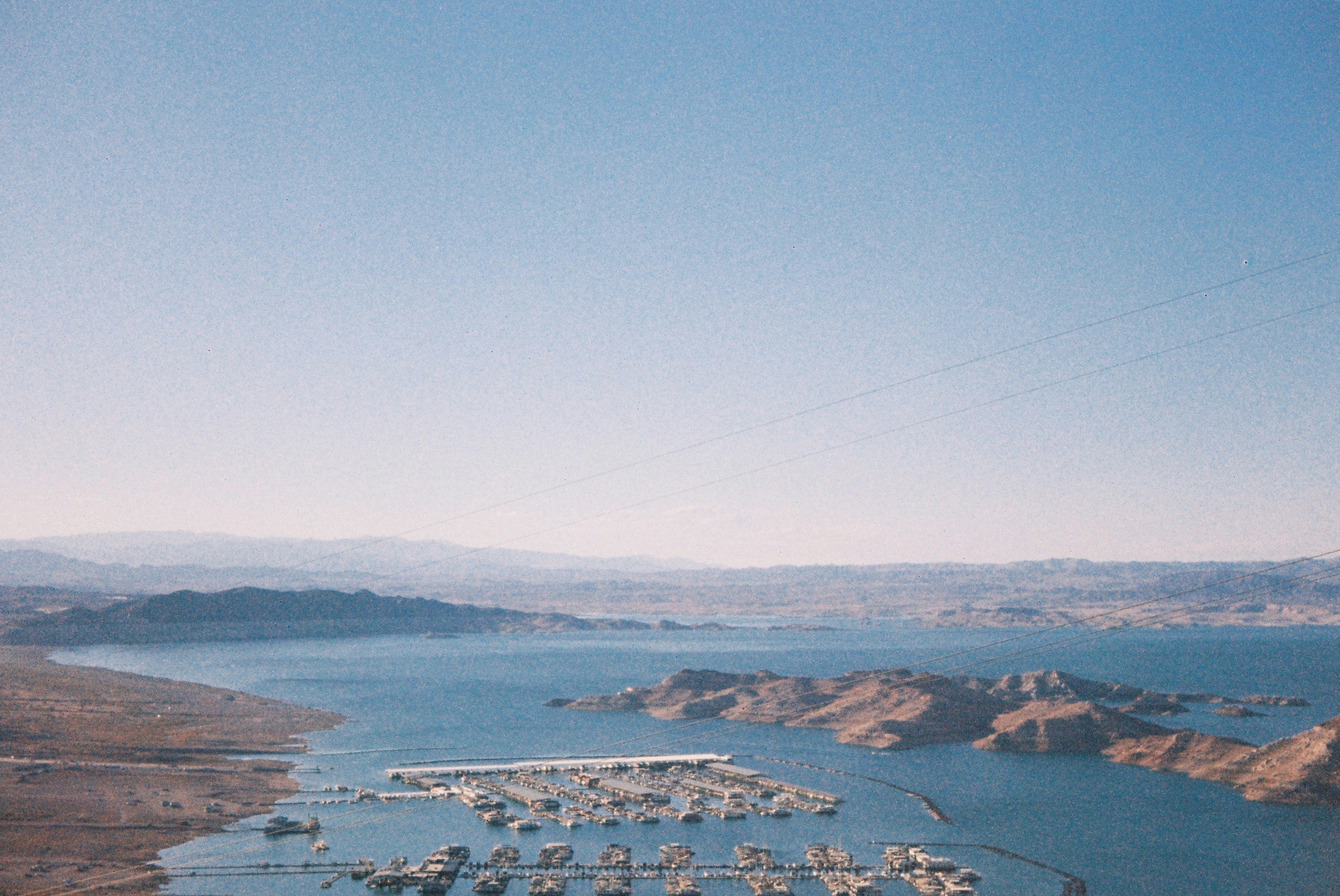 Une marina avec de nombreux bateaux sur un grand lac entouré de collines arides.