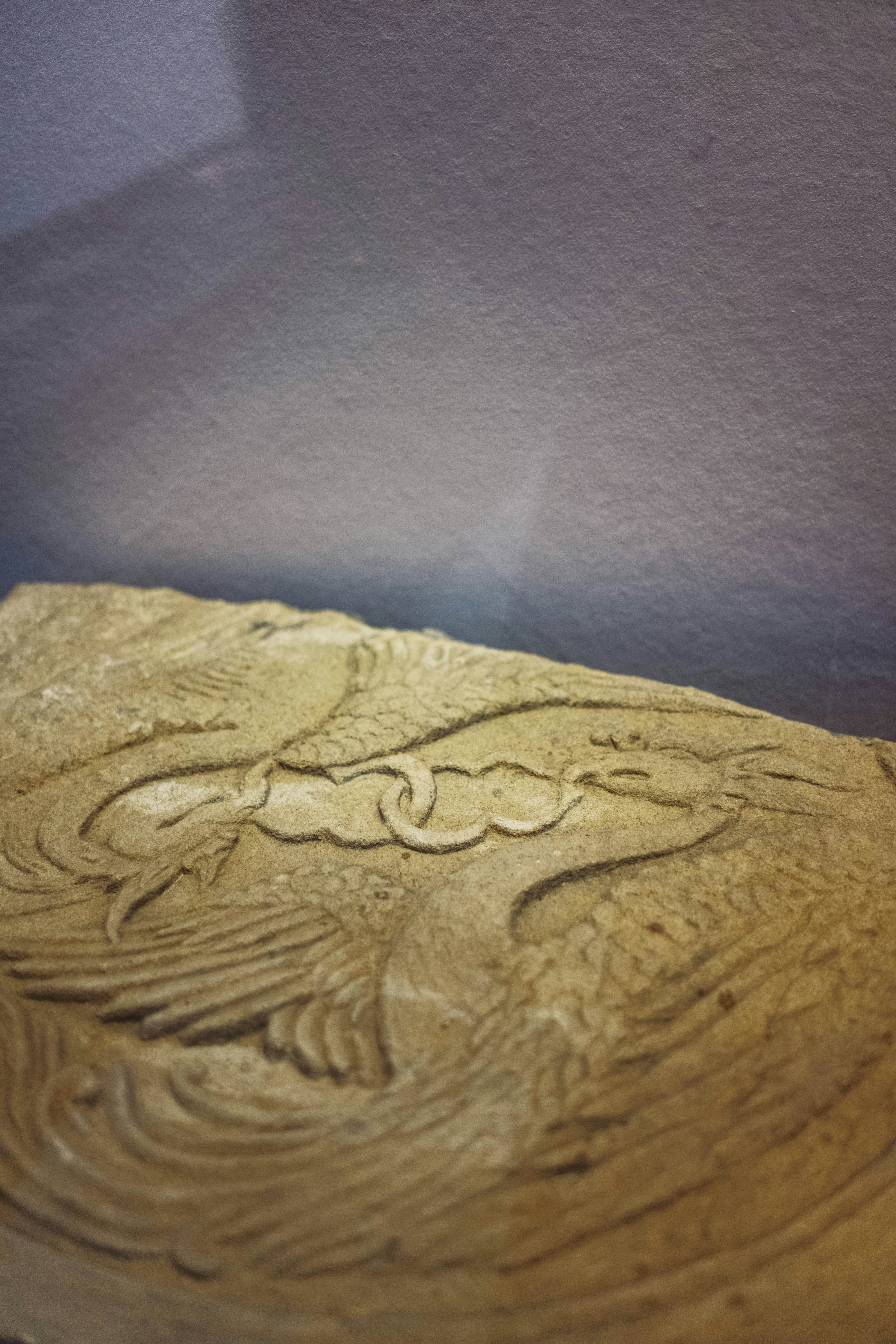 Un relief en pierre sculptant un phénix avec des ailes déployées sur une surface texturée