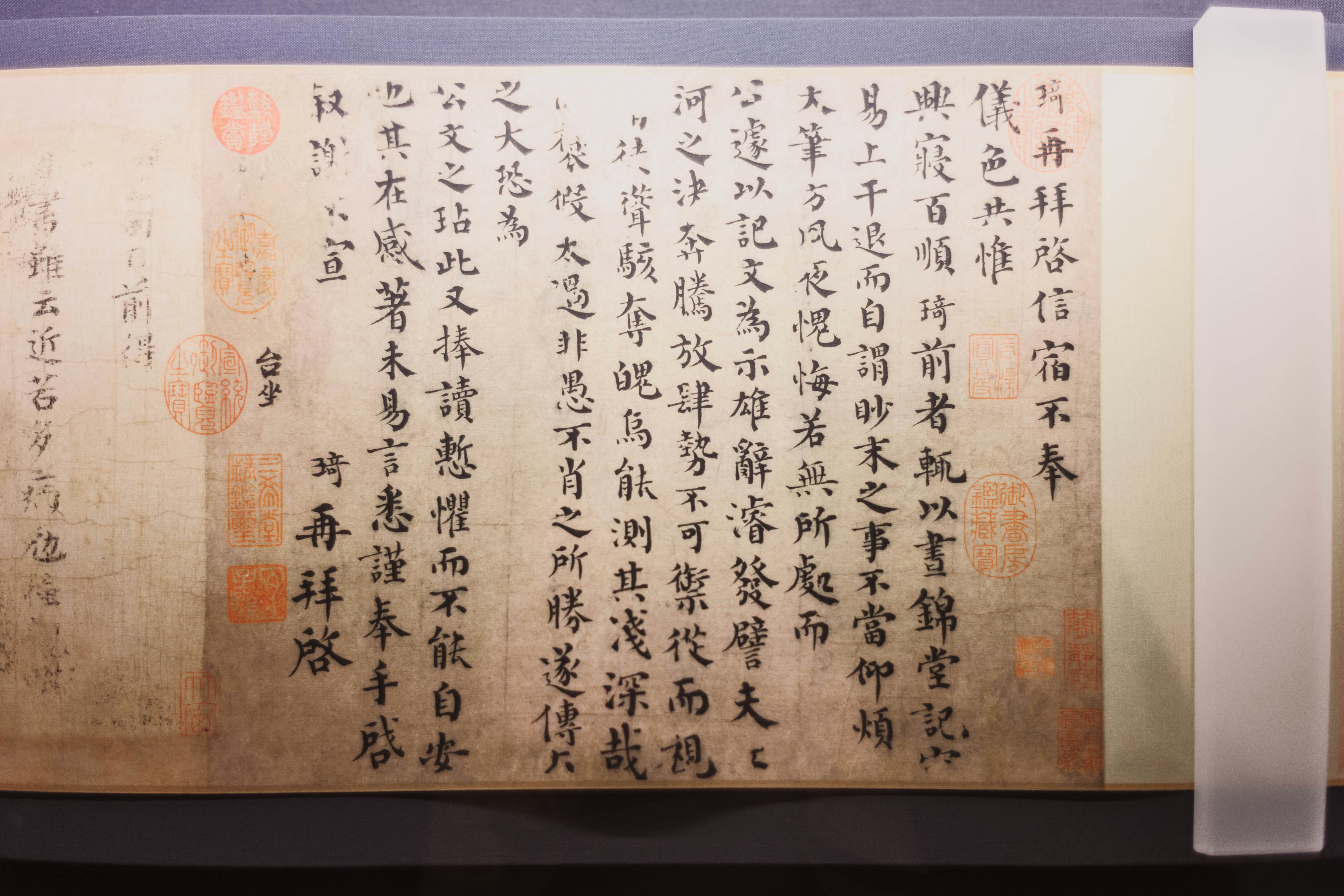 A vertical scroll featuring traditional Chinese calligraphy with red ink stamps on aged paper