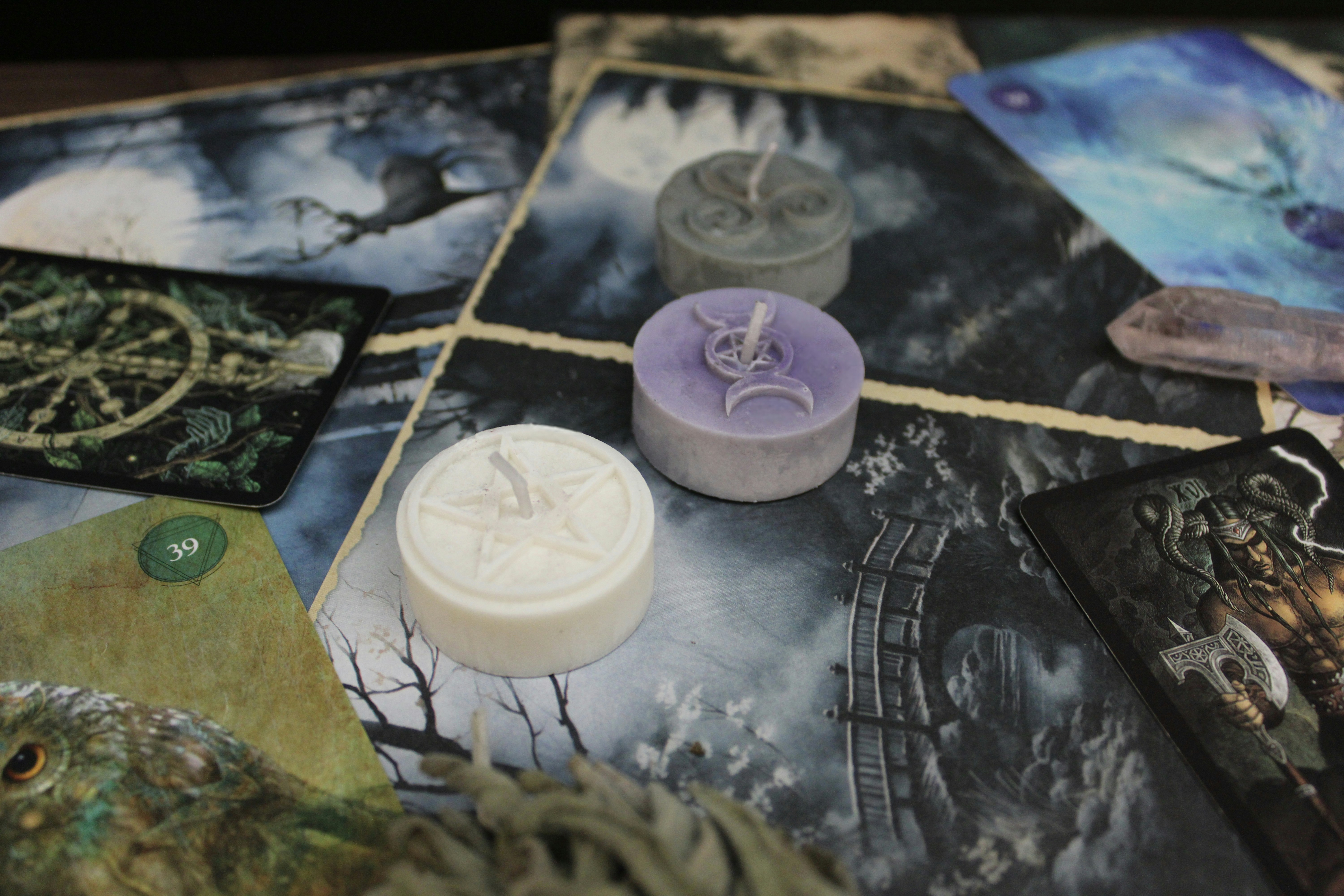 Small ritual candles arranged over tarot cards on an altar