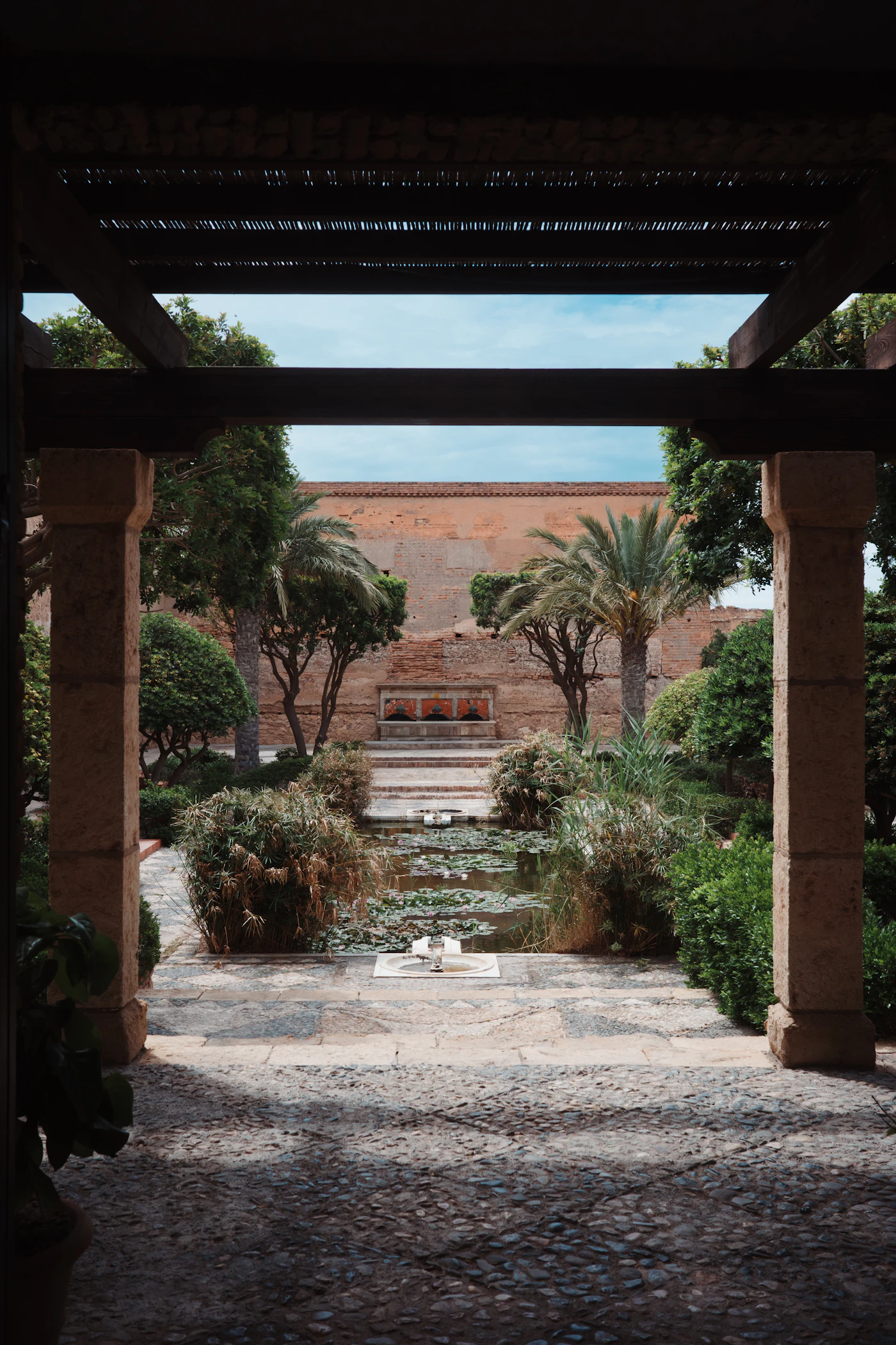 A stone courtyard with a lily pond, framed by a timber pergola.