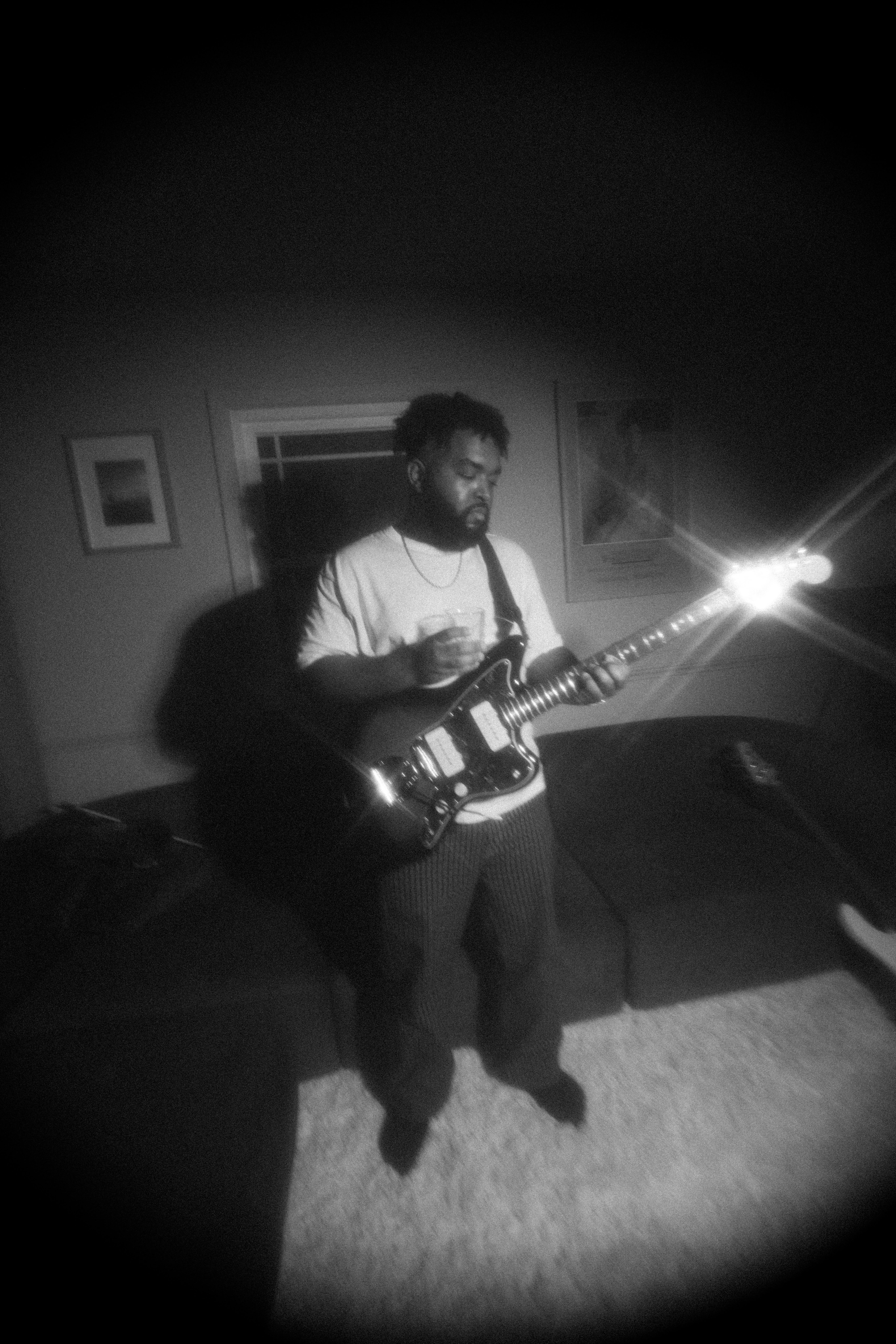 A man with a beard playing an electric guitar in a dimly lit room.