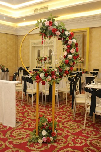 Gold floral arch of red and white roses in a banquet hall