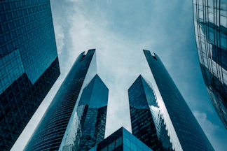 Low angle view of modern glass skyscrapers reaching toward a cloudy blue sky