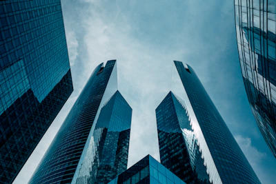 Low angle view of modern glass skyscrapers reaching toward a cloudy blue sky