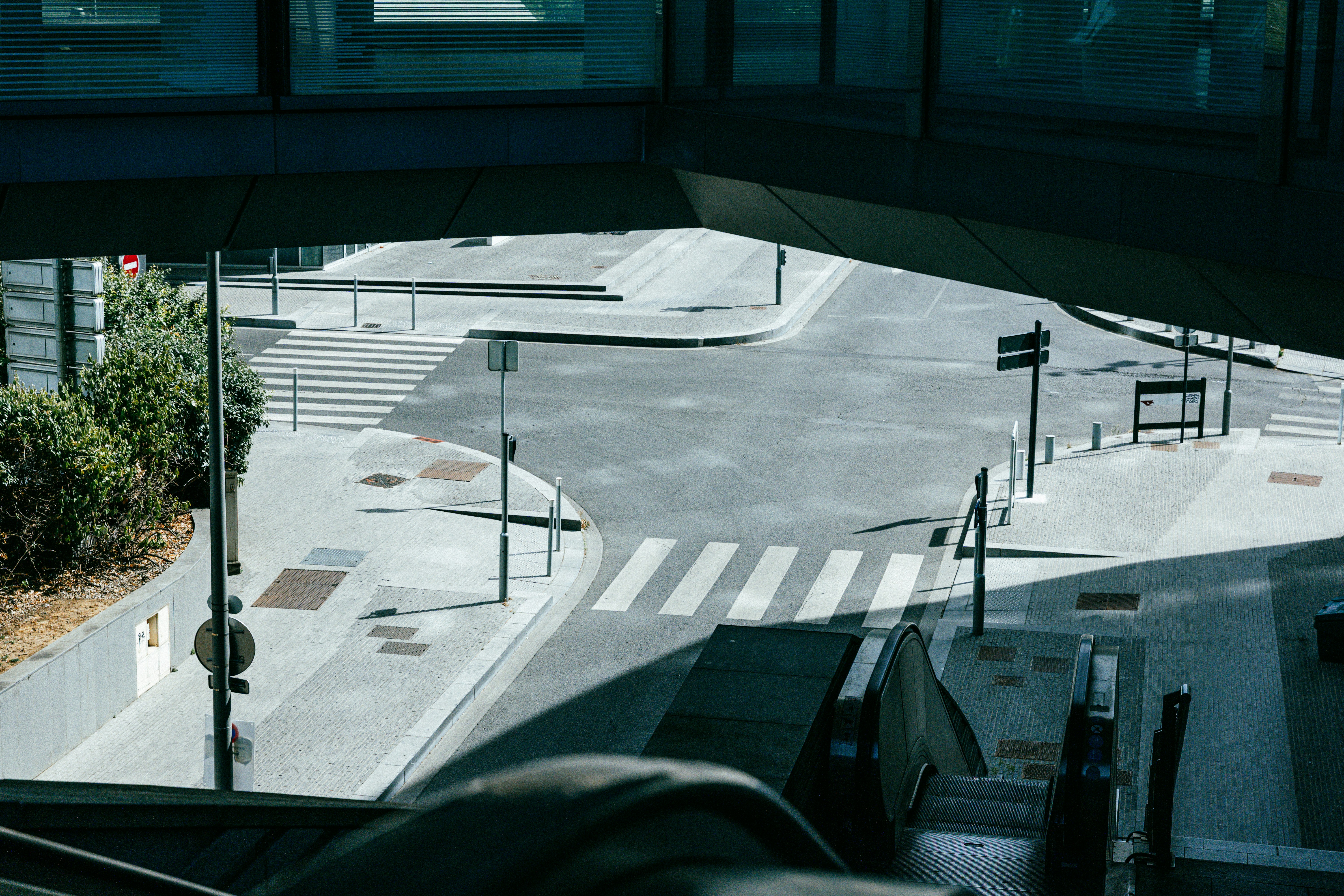 An empty street intersection with crosswalks viewed from an elevated walkway