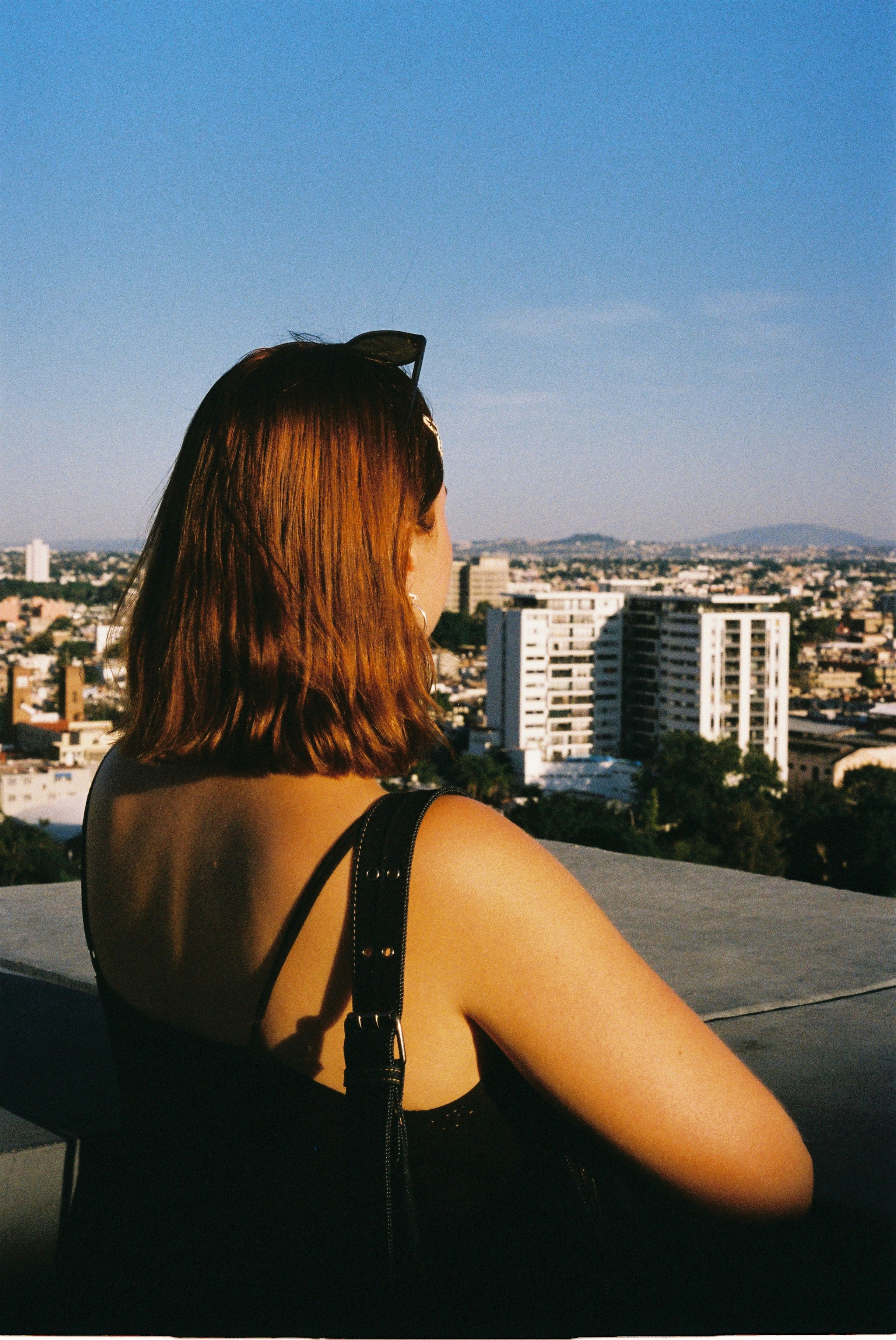 A woman with auburn hair looking out over a sprawling city skyline
