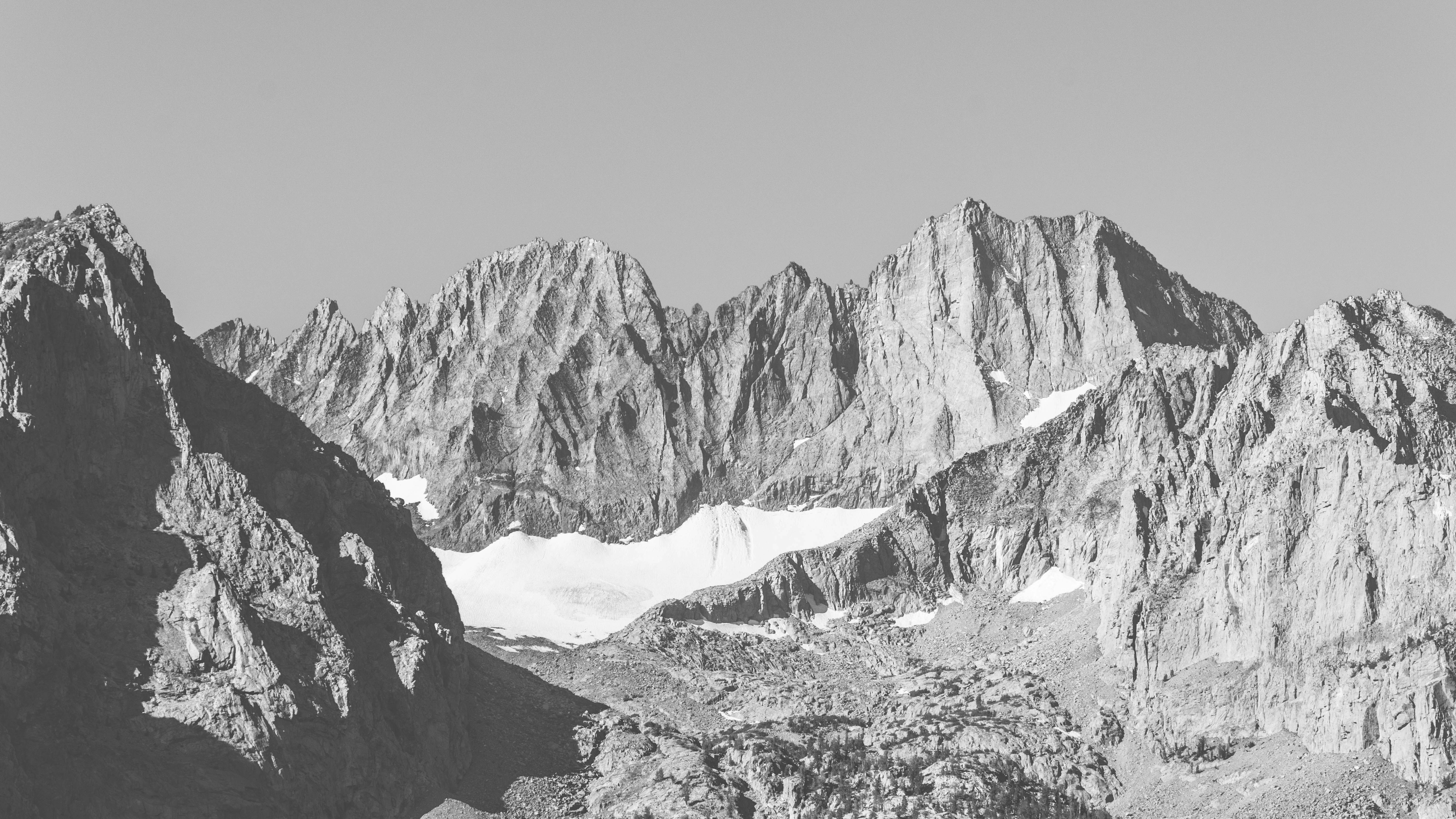 Jagged mountain peaks with patches of snow in a black and white landscape