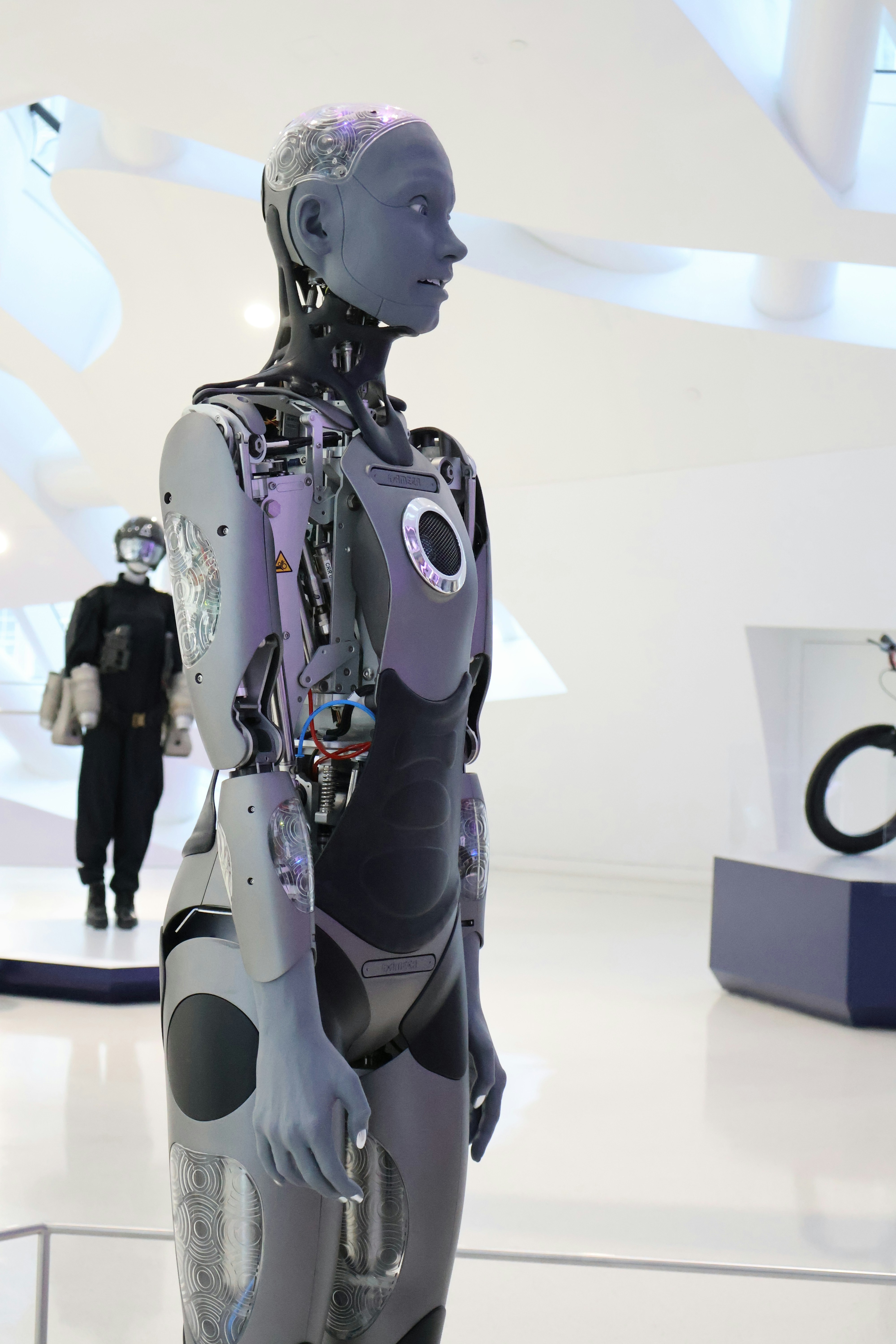 Un robot humanoïde aux articulations mécaniques exposées dans un espace d’exposition blanc éclatant