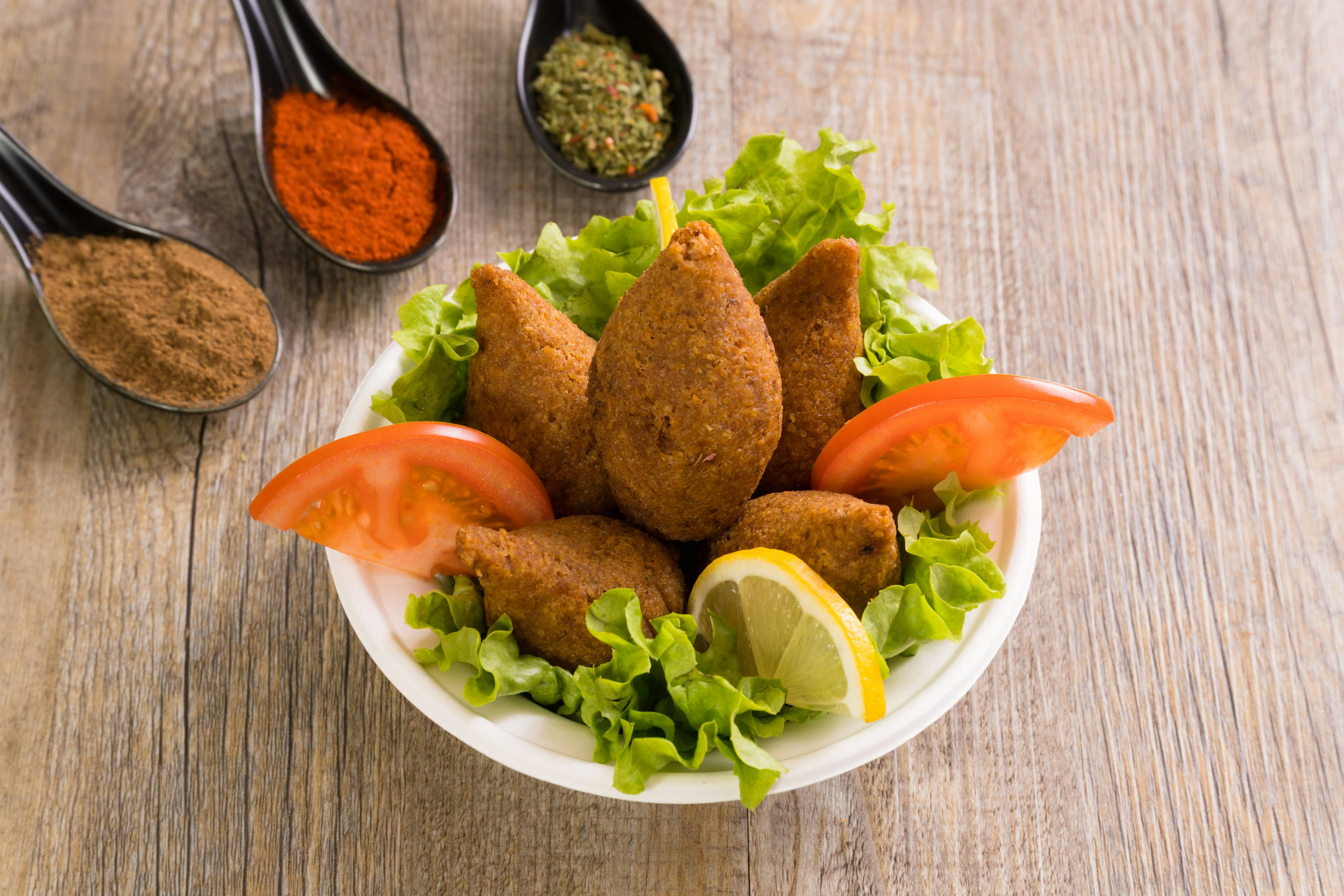 Fried kibbeh on lettuce with tomato and lemon