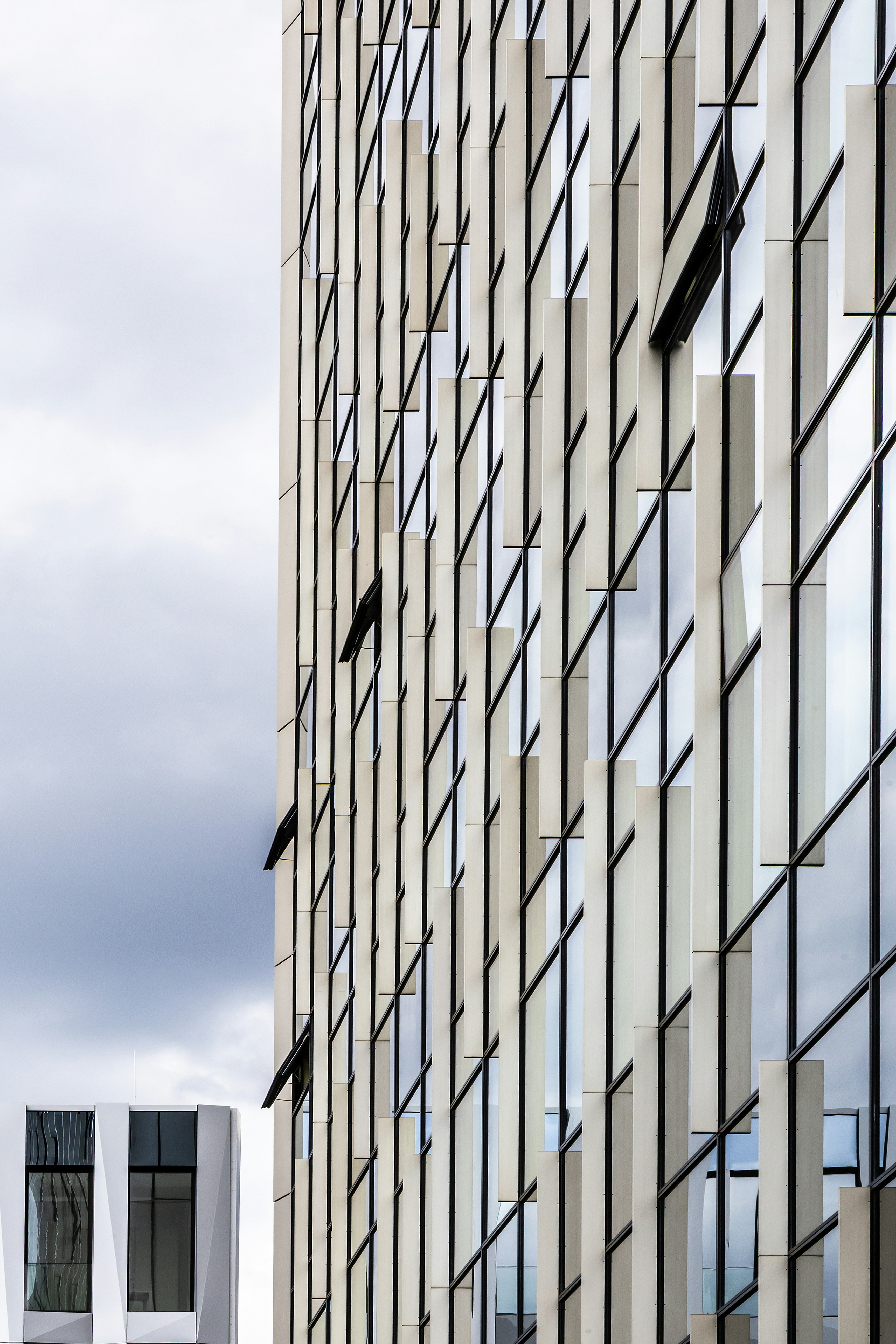 Une façade moderne avec des panneaux blancs verticaux et des vitres réfléchissantes