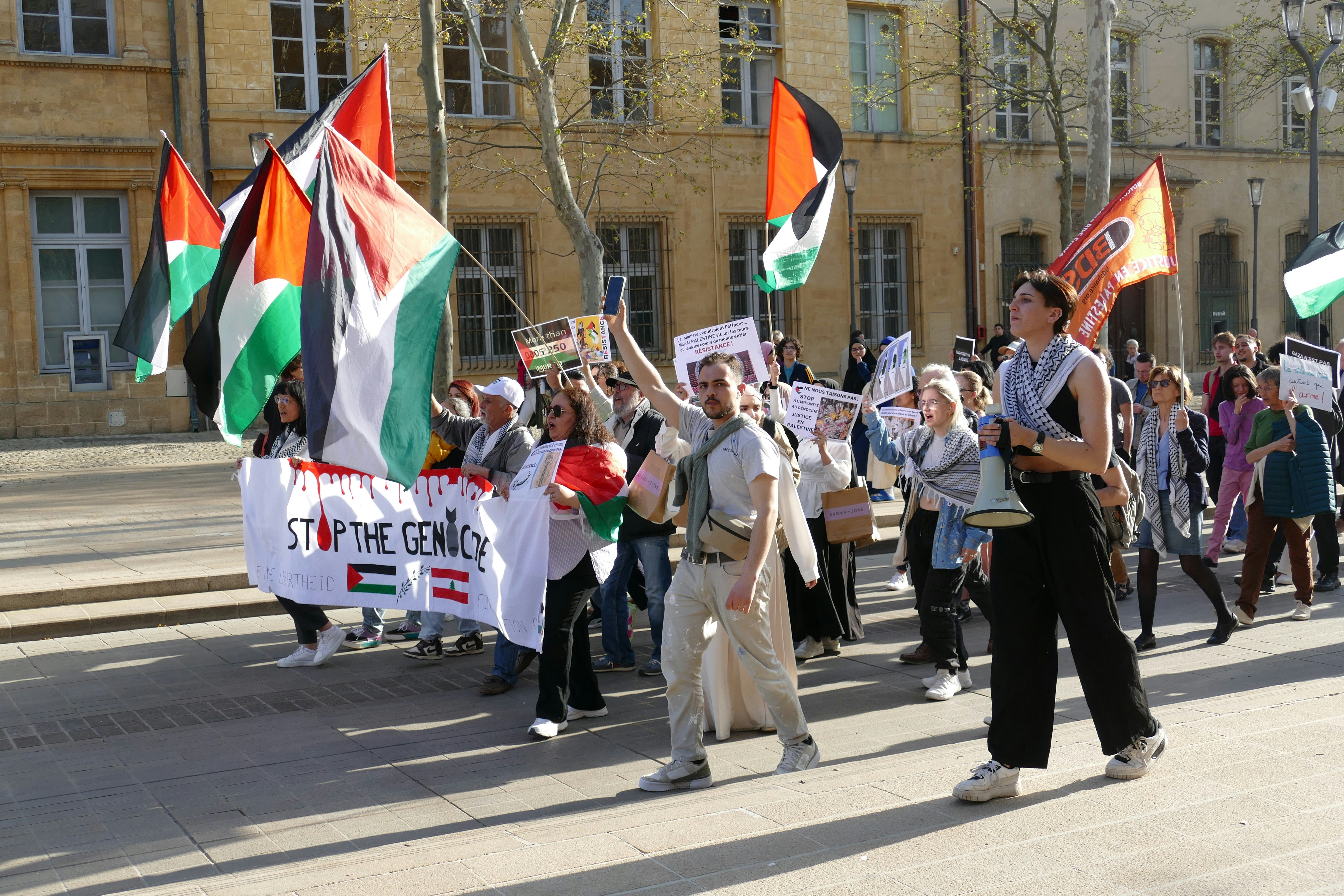 A group of people marching with flags and banners in a city square