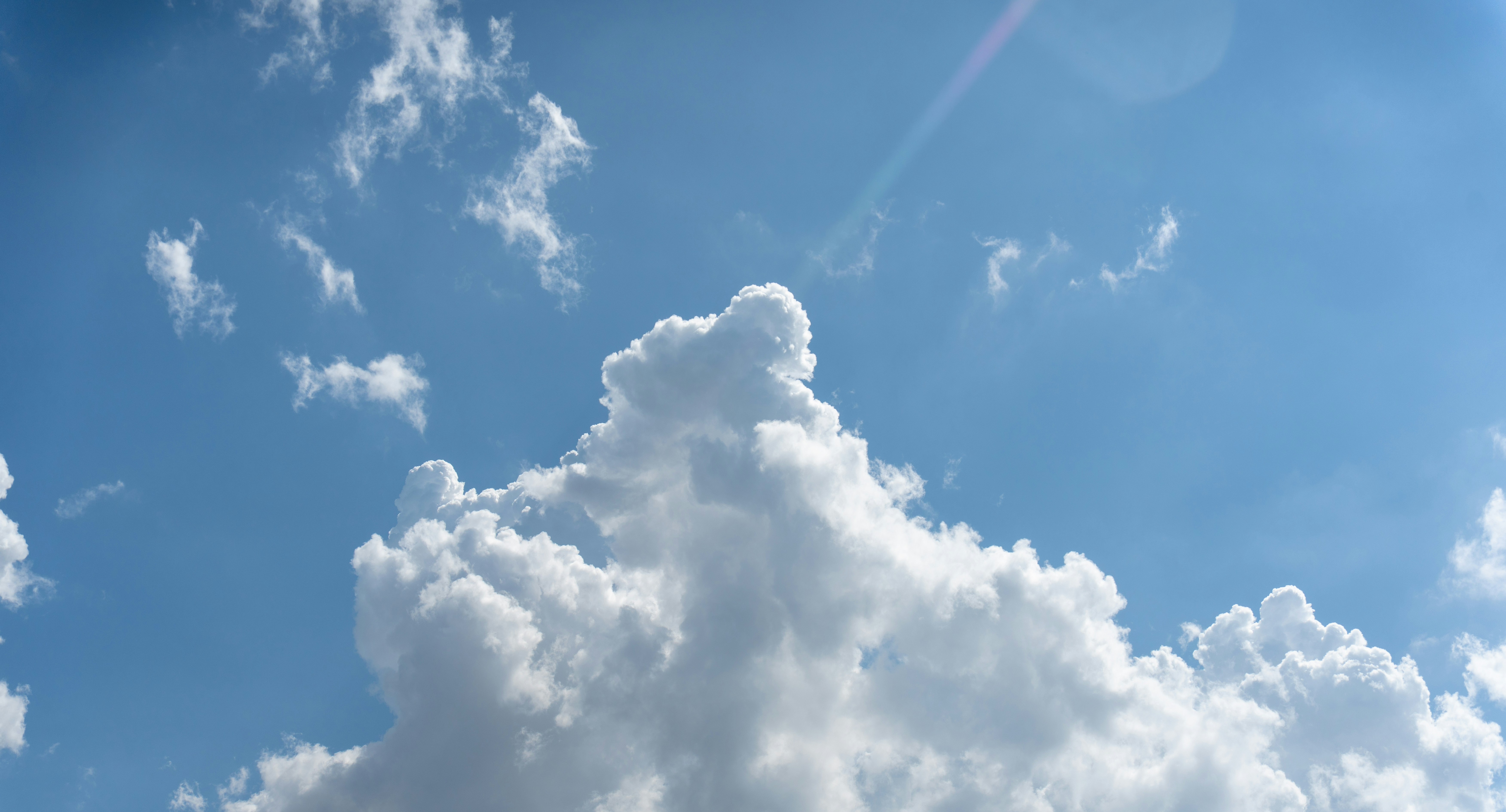 Fluffy white cumulus clouds drifting across a bright blue sky.