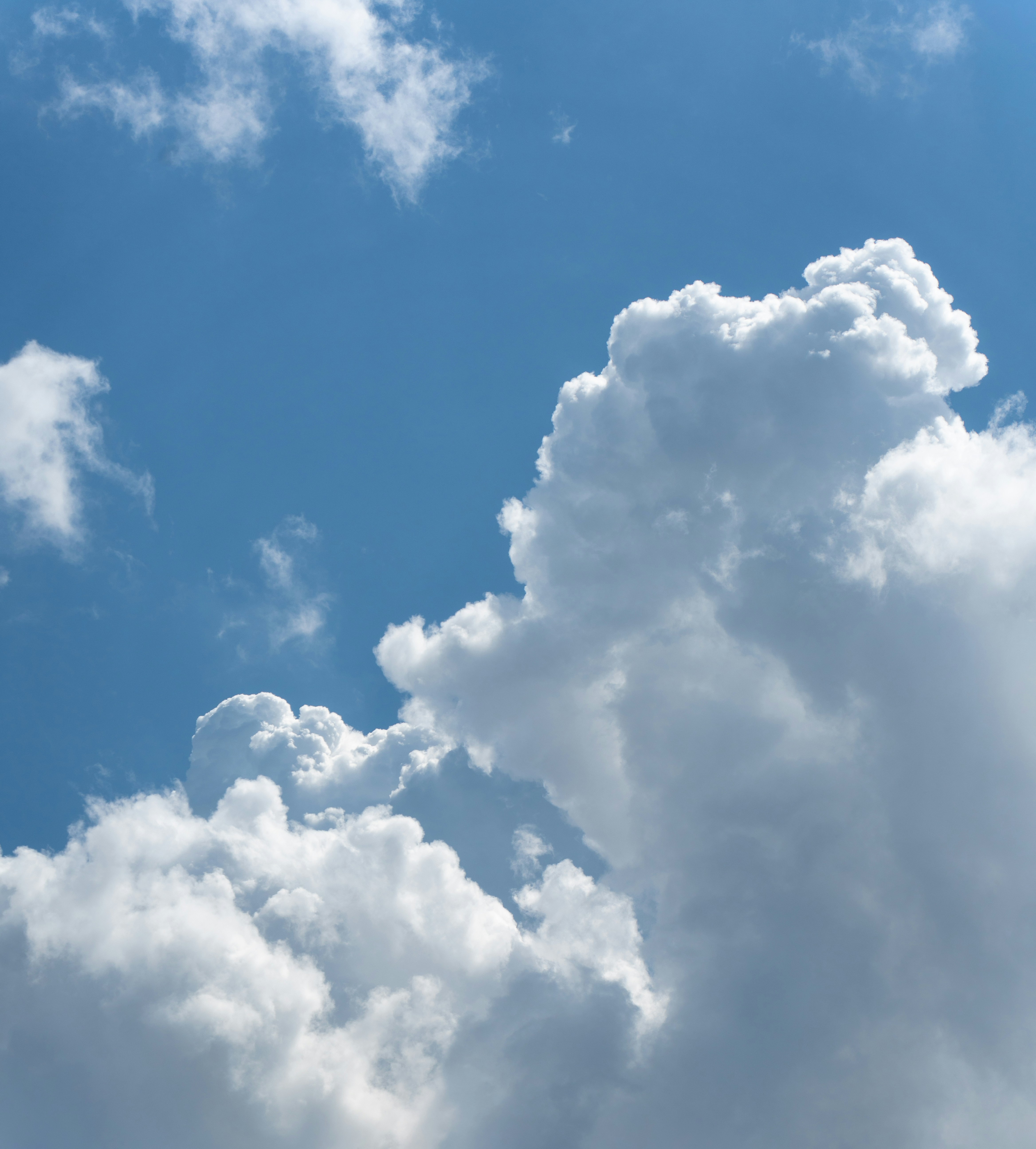 Fluffy white cumulus clouds drifting across a bright blue sky.