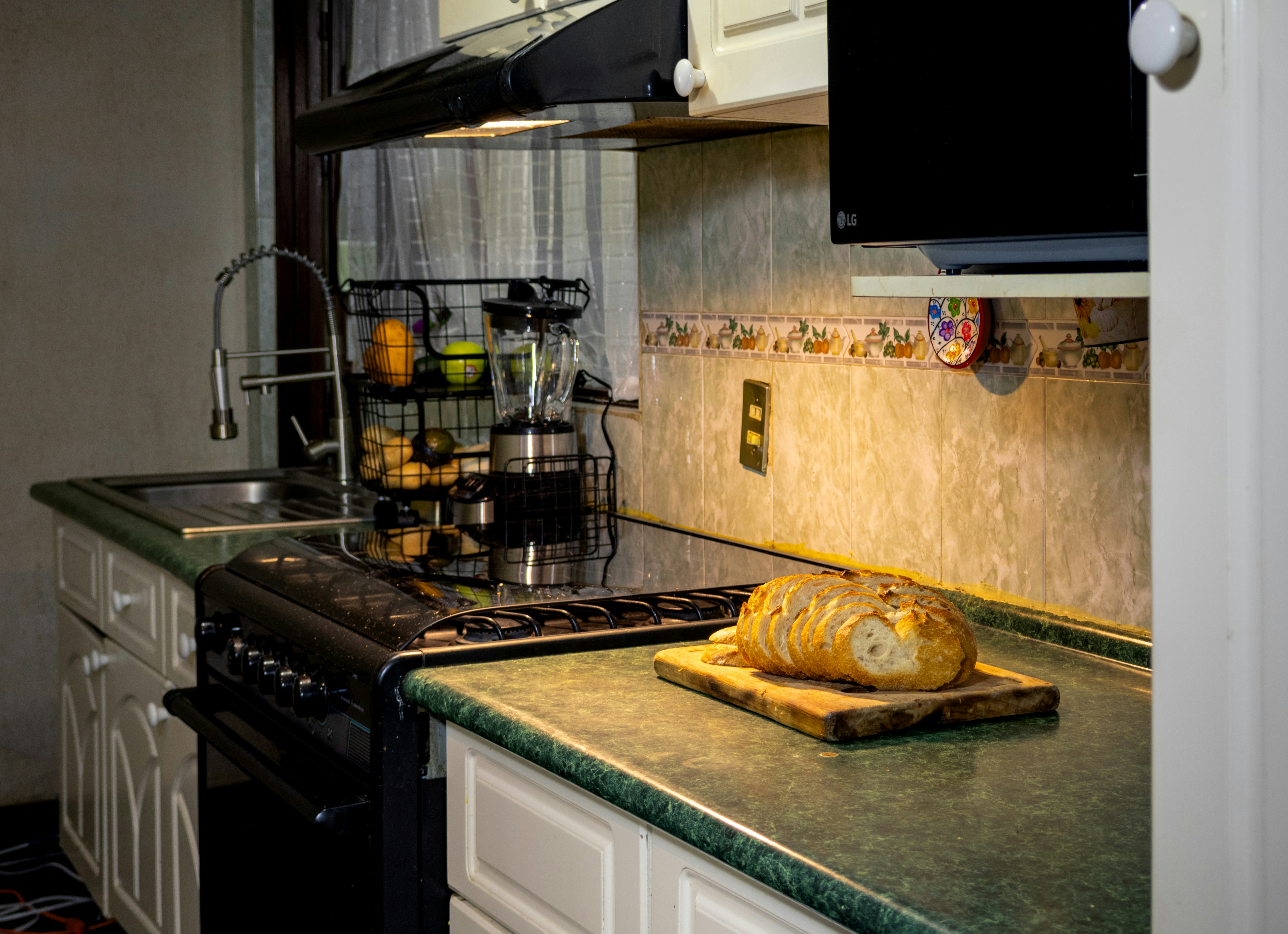 Sliced bread on a wooden cutting board on a green kitchen counter