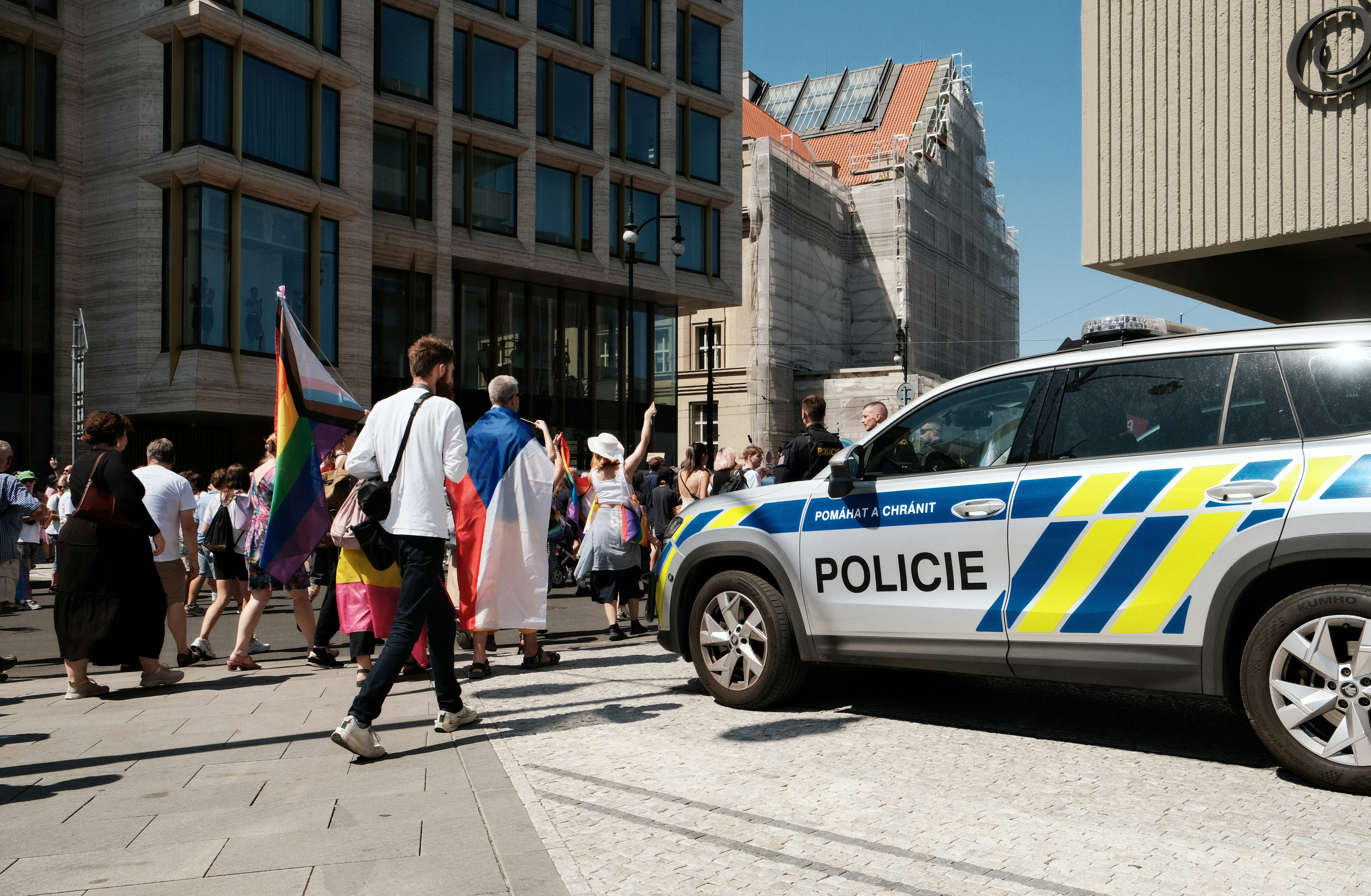 Menschen, die während einer Pride-Parade in Prag an einem Polizeiauto vorbeigehen.