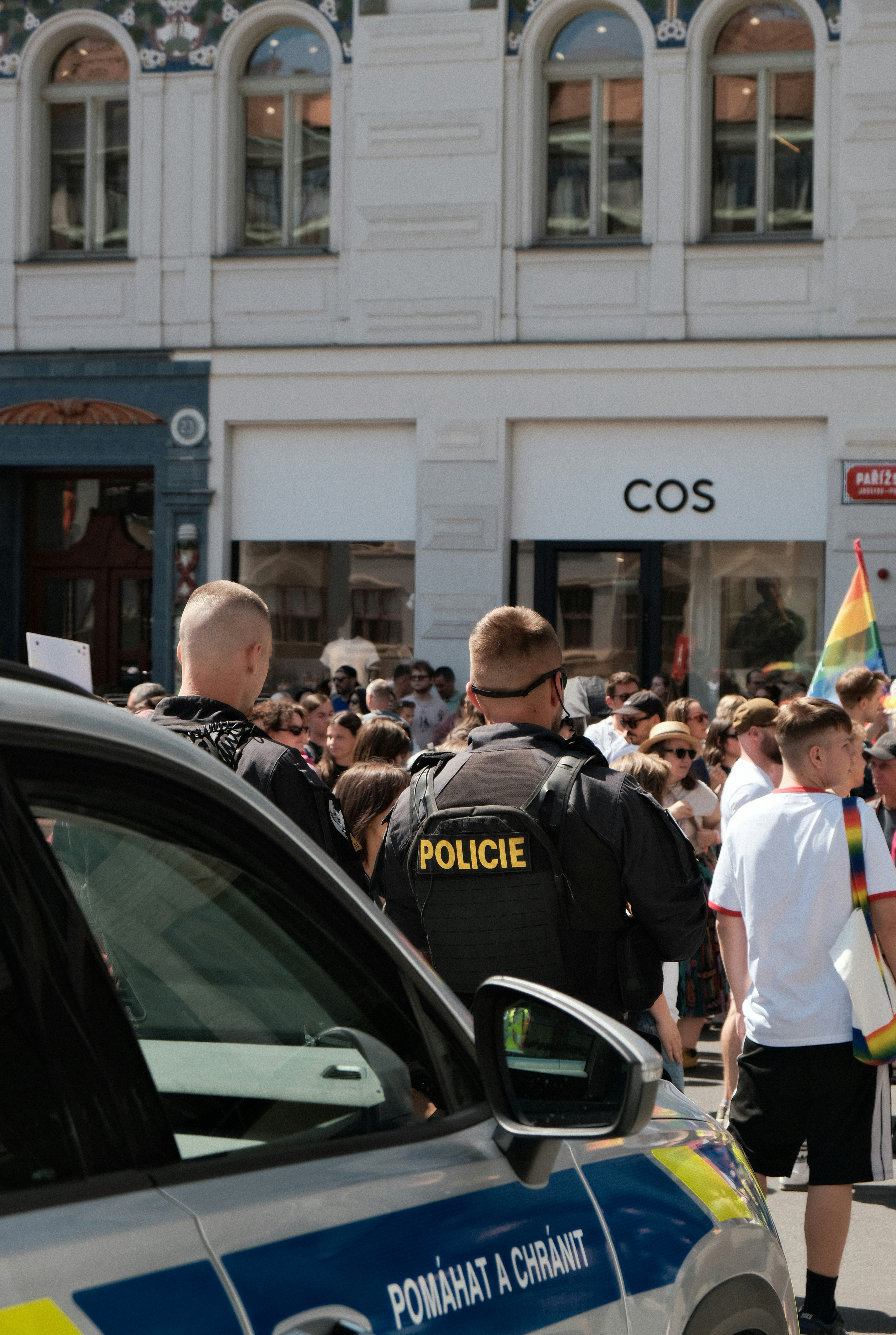 Polizisten in schwarzen Uniformen stehen bei einer öffentlichen Veranstaltung in der Nähe einer Menschenmenge.