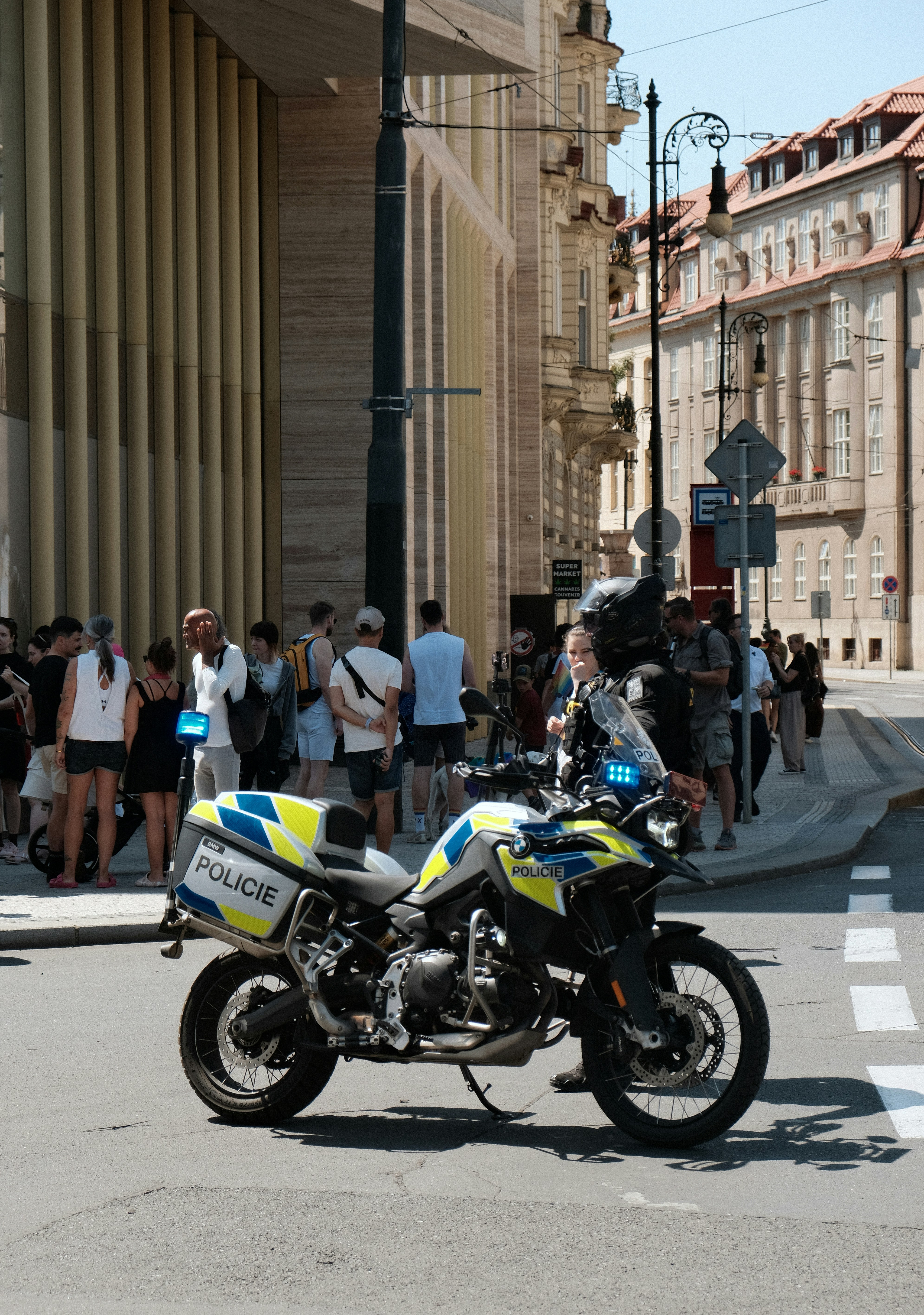 Ein Polizeimotorrad, das auf einer Stadtstraße geparkt ist, mit Fußgängern im Hintergrund.