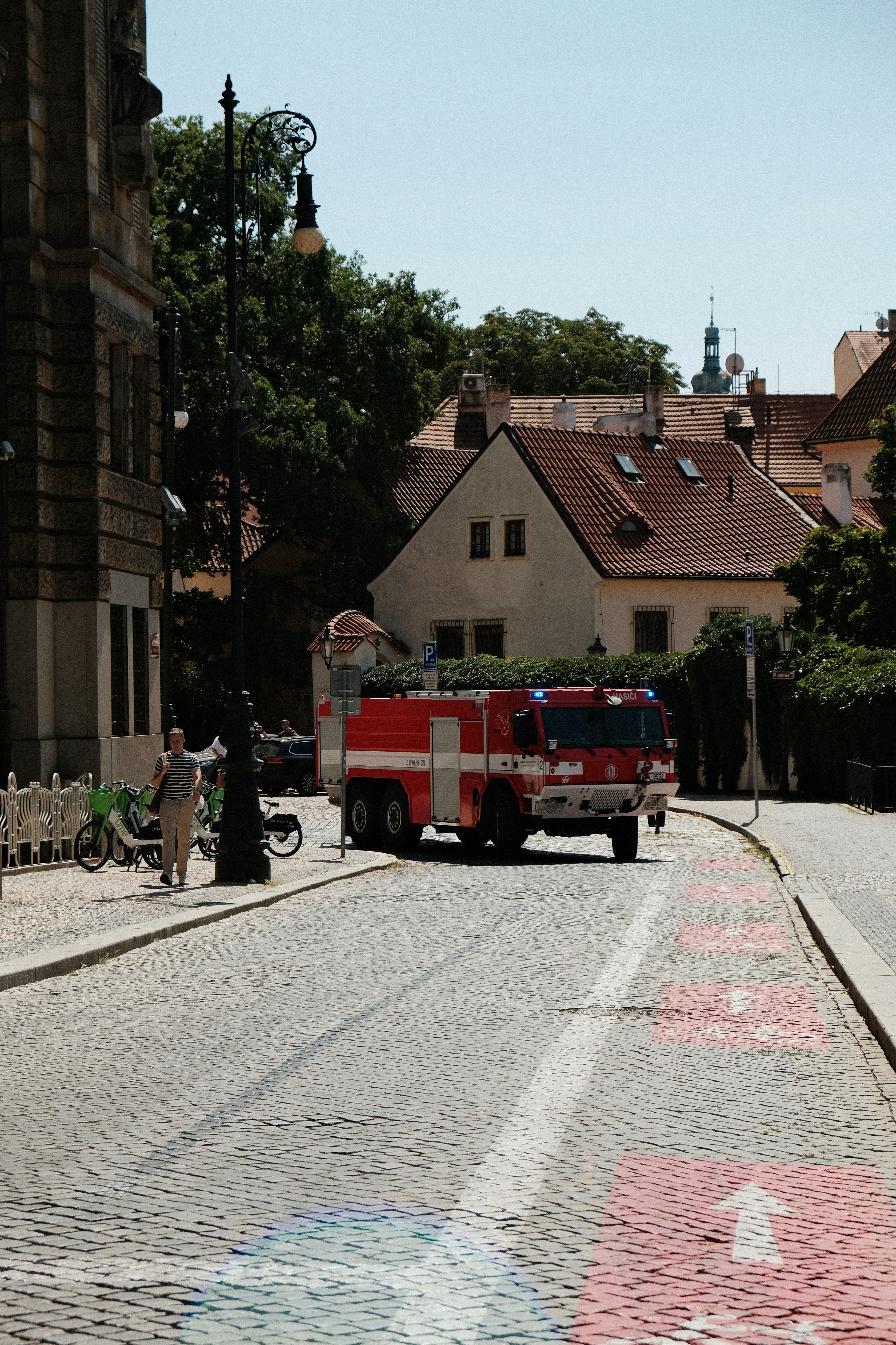 Ein rotes Feuerwehrauto mit blauen Lichtern auf einer Kopfsteinpflasterstraße in Prag.