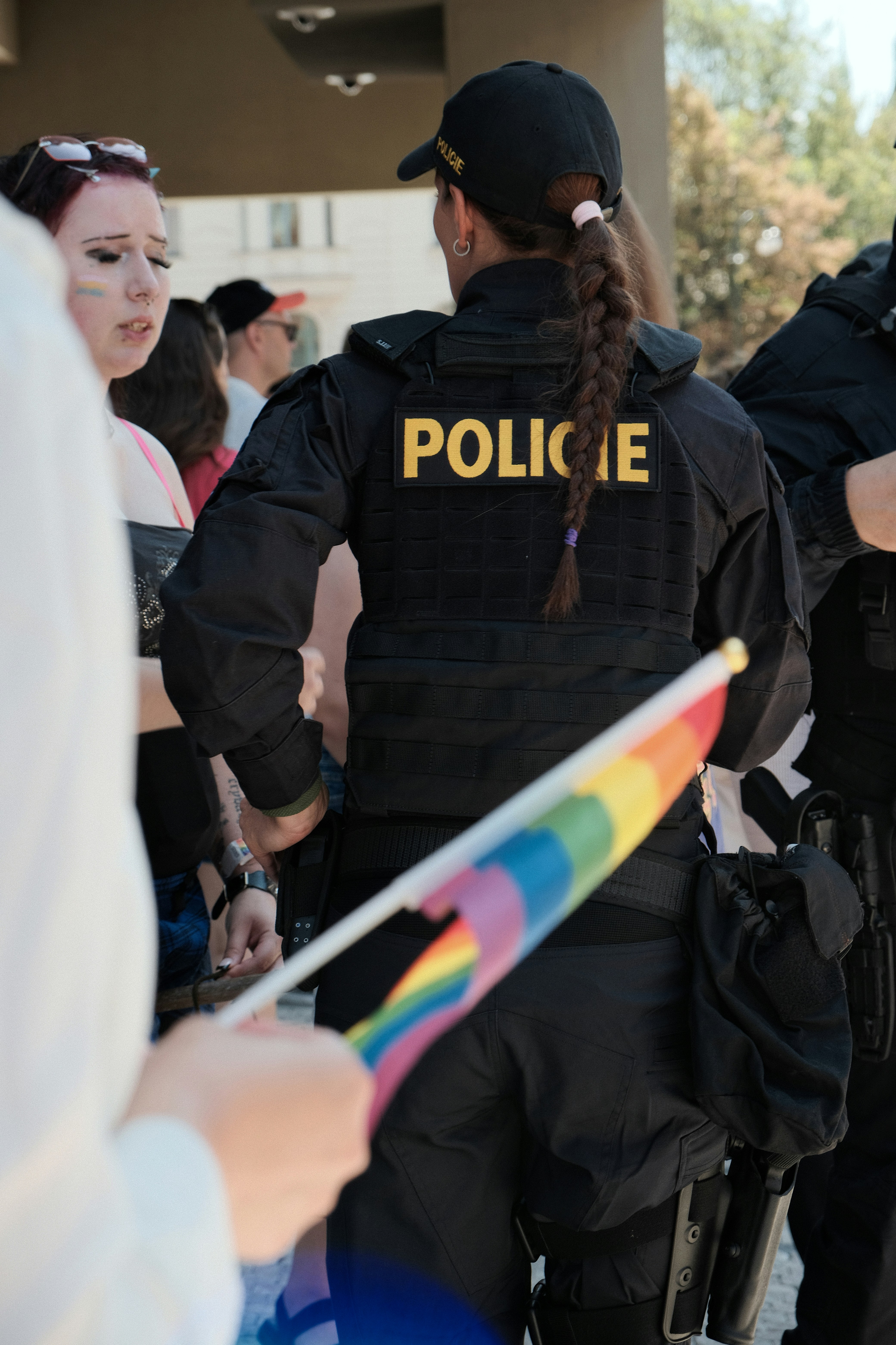 Ein Polizist in schwarzer taktischer Ausrüstung hält eine kleine Regenbogenflagge.