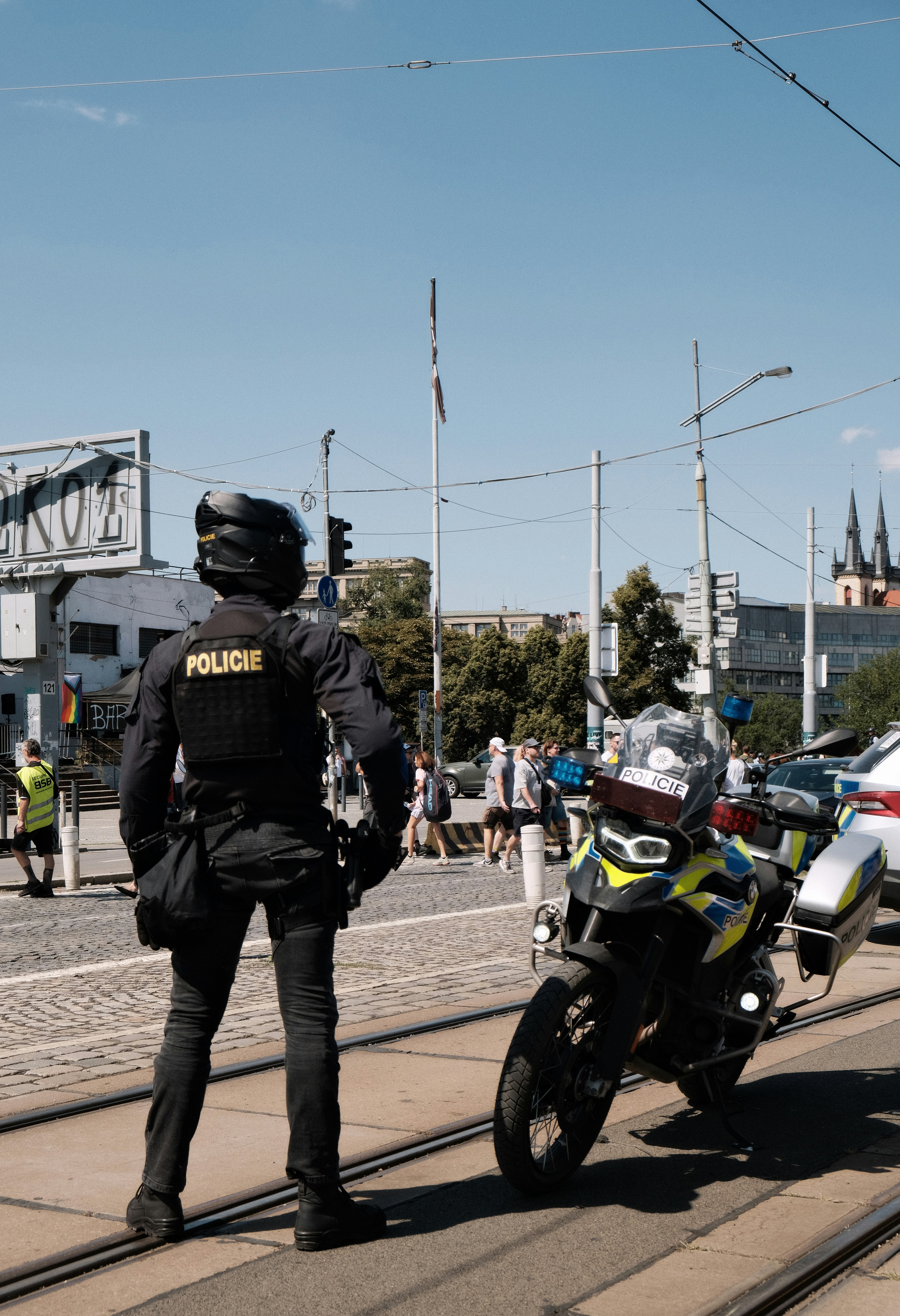 Ein Polizist in schwarzer taktischer Ausrüstung steht neben einem Motorrad auf den Straßenbahngleisen.
