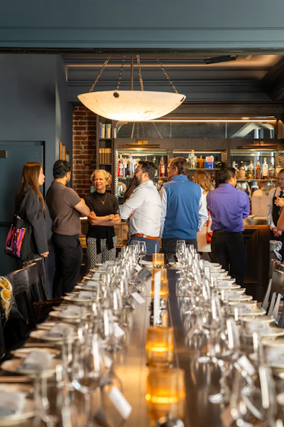 A group in conversation at a long table in a dim restaurant