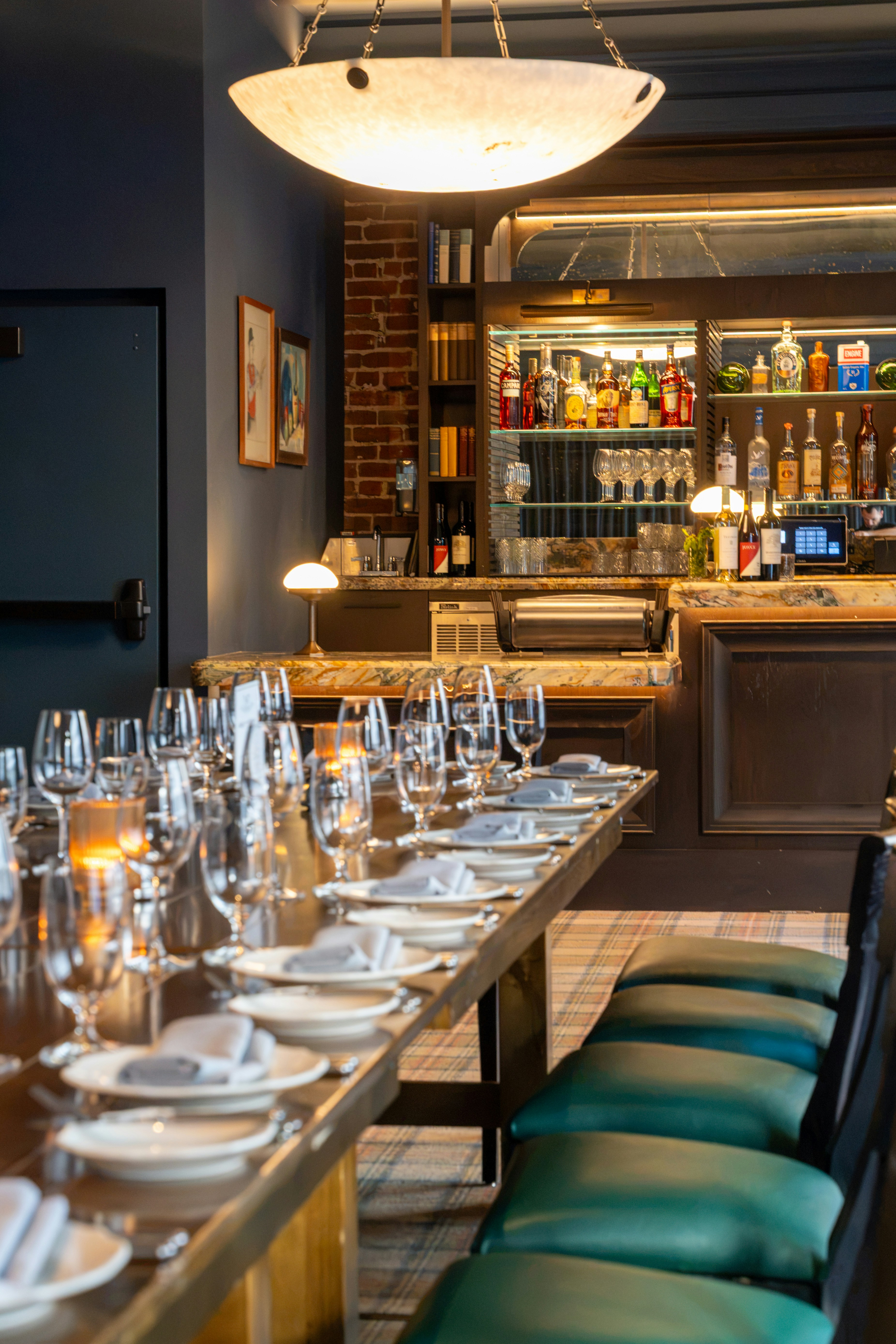 A long dining table set with glasses and napkins in a dimly lit restaurant