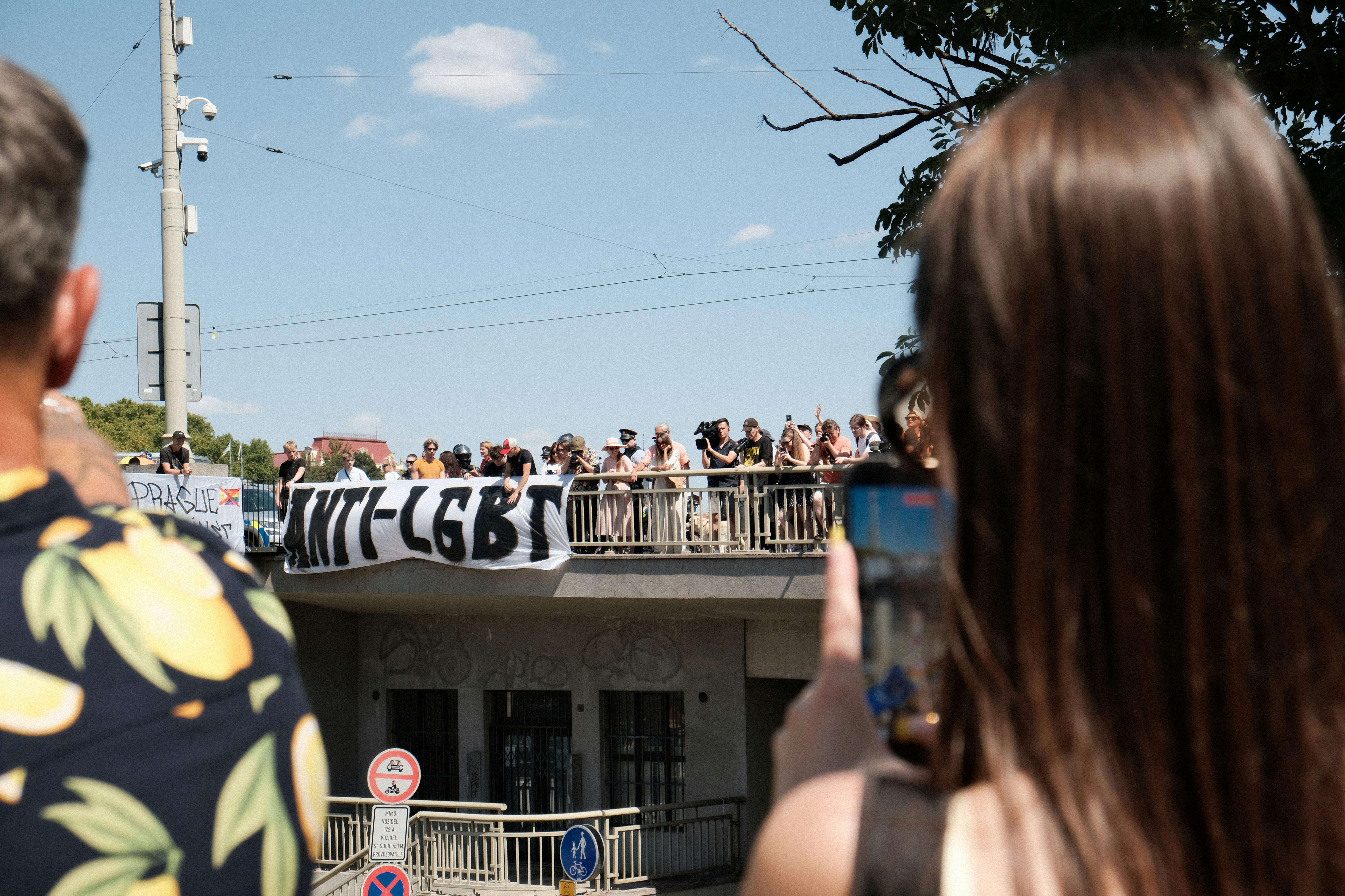 Eine Menschenmenge hält ein Banner mit der Aufschrift "ANTI-LGBT" auf einer Brücke.
