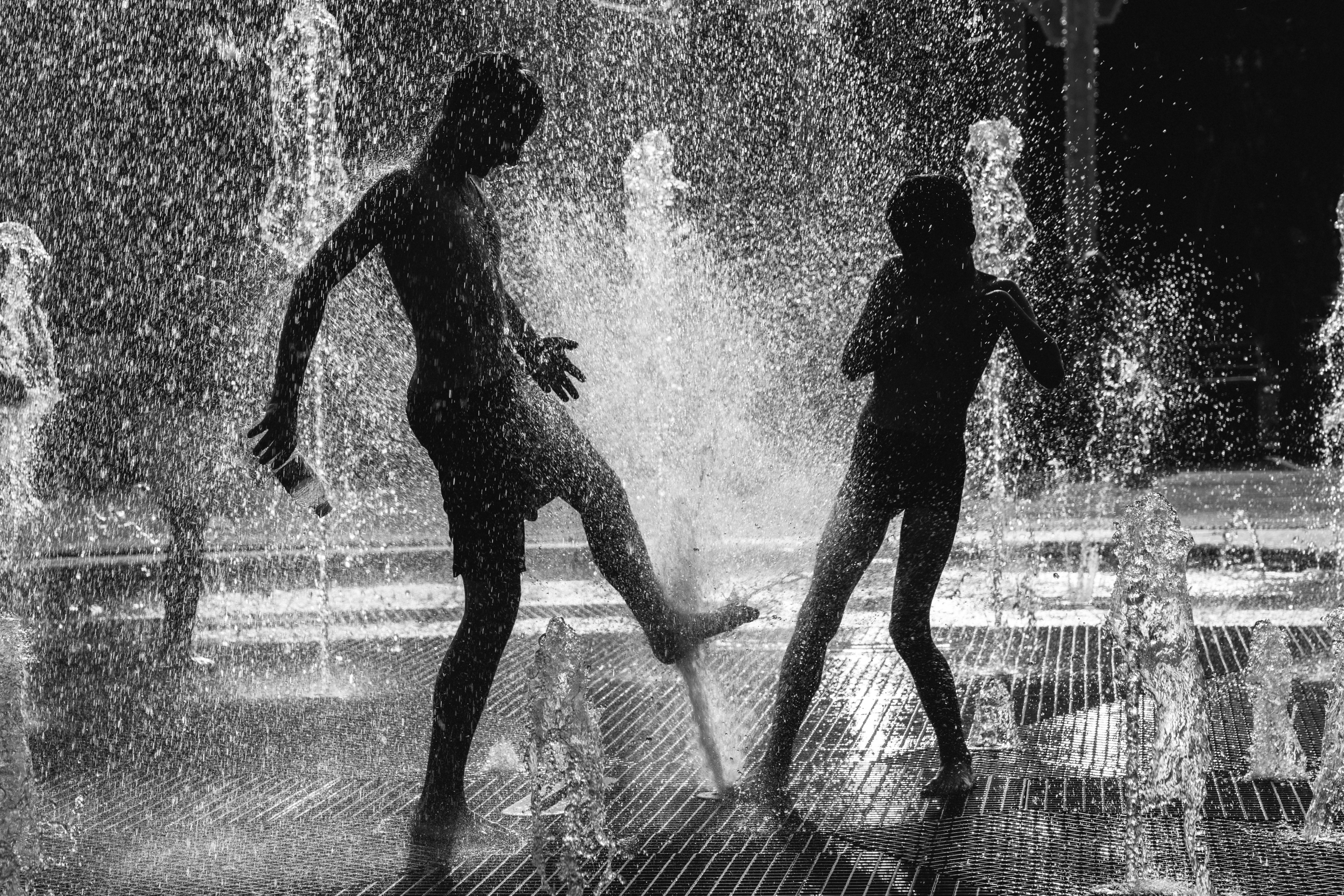 Deux personnes en silhouette jouant dans une fontaine avec de l’eau qui éclaboussait