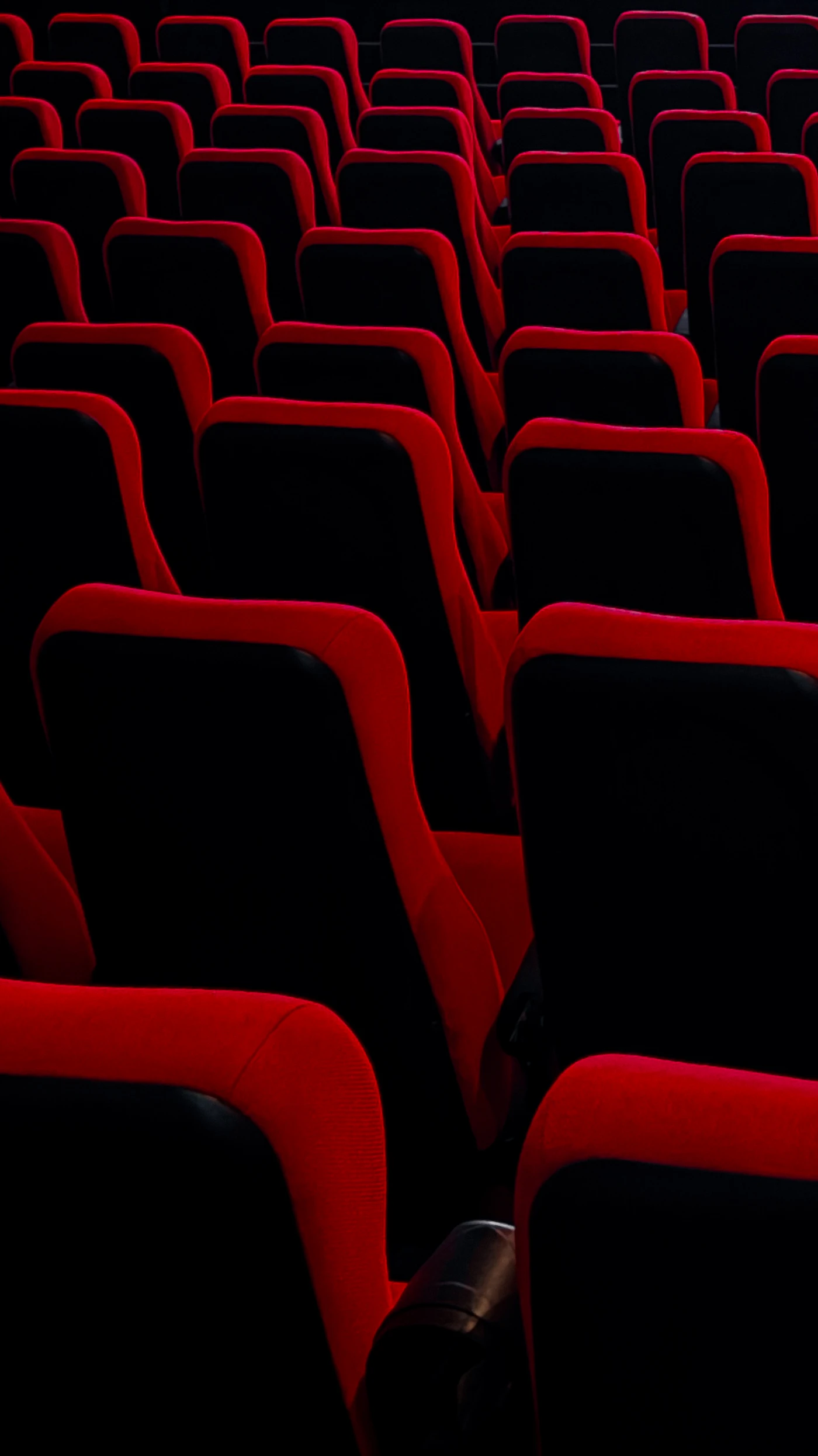 Rows of empty red and black cinema seats in a dark theater