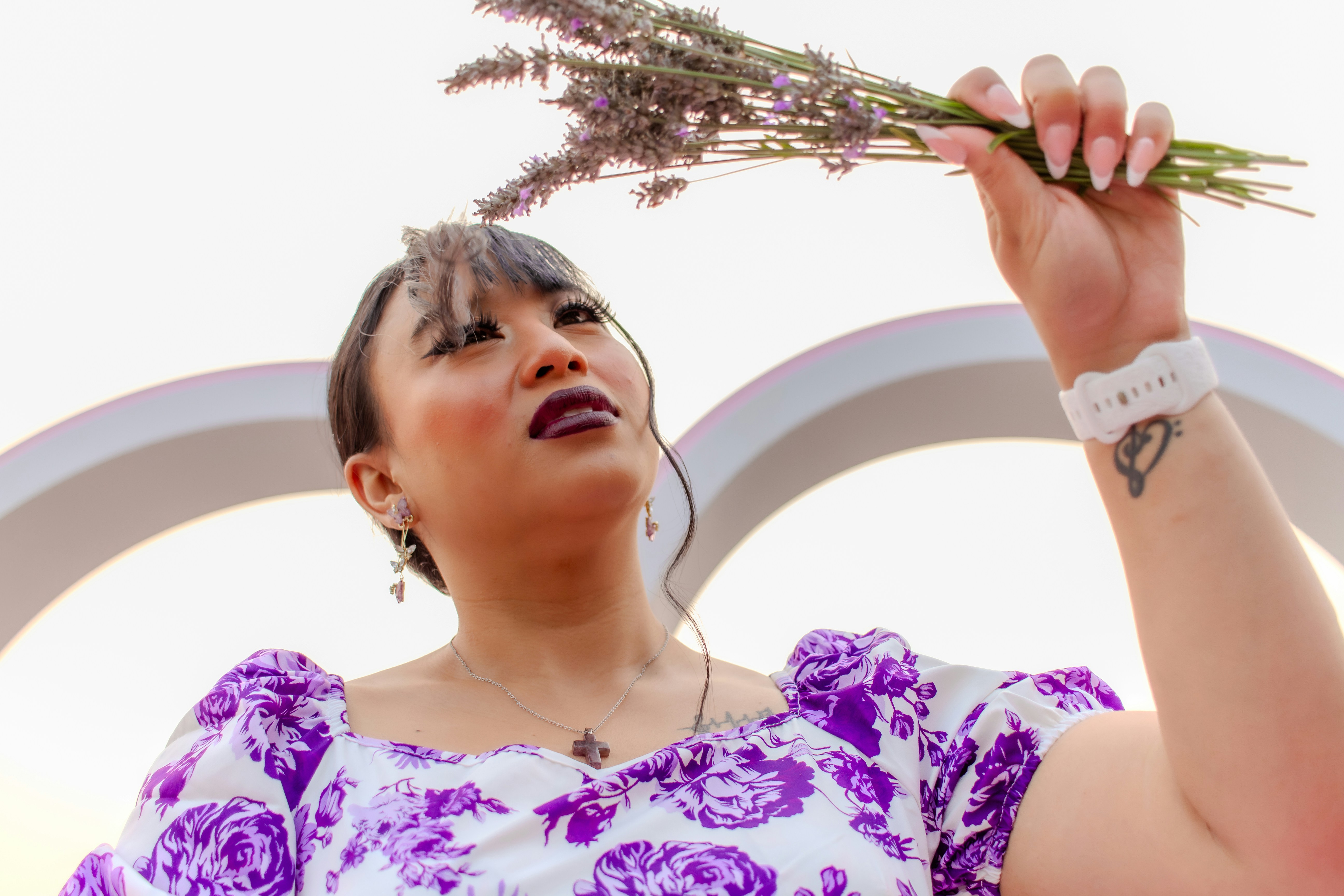 紫色の花柄トップスを着て、ラベンダーの花束を手にした女性。