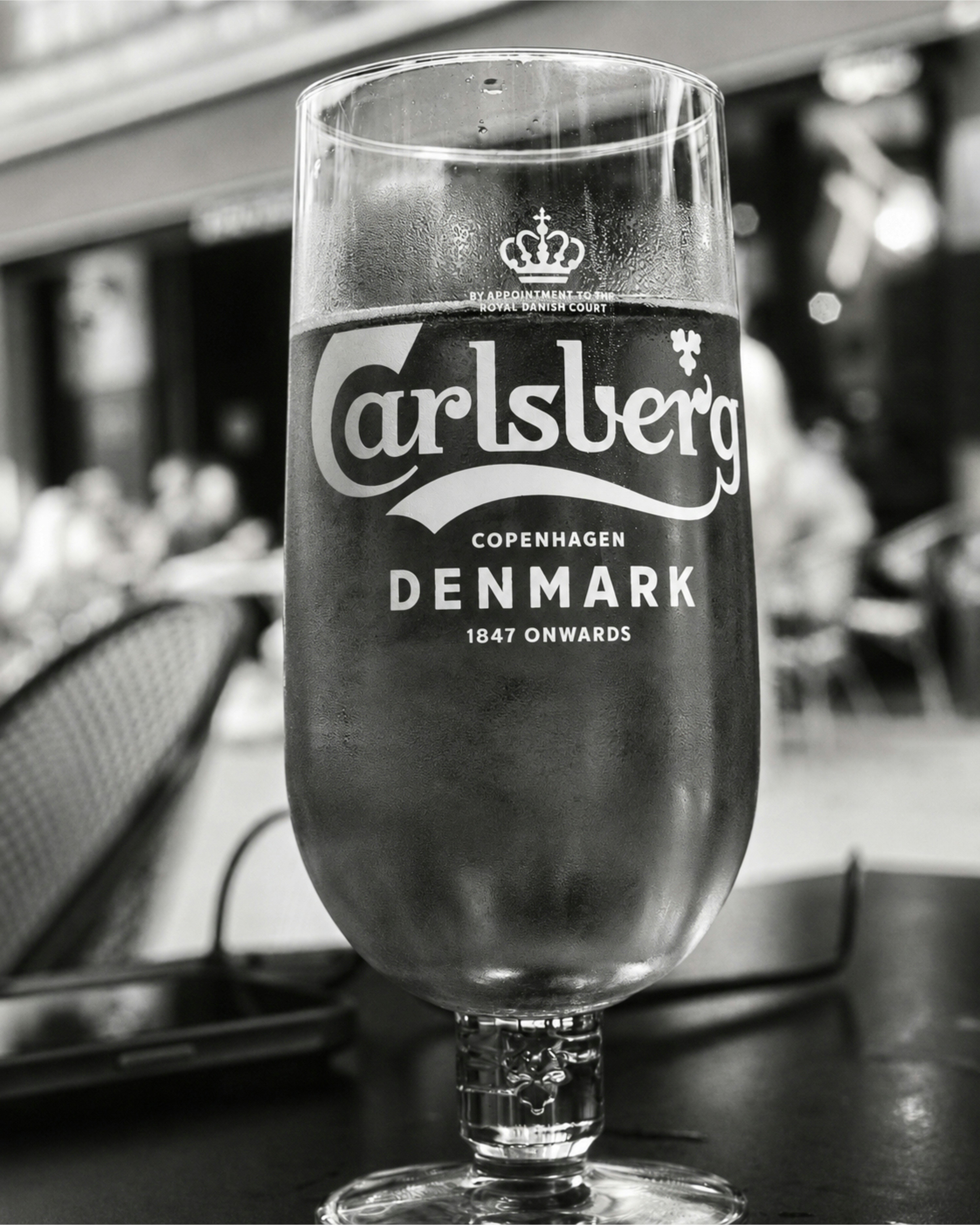 A glass of beer with a logo on a table in a cafe
