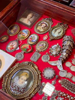 Antique portrait miniatures and jewelry displayed on a bright red velvet surface