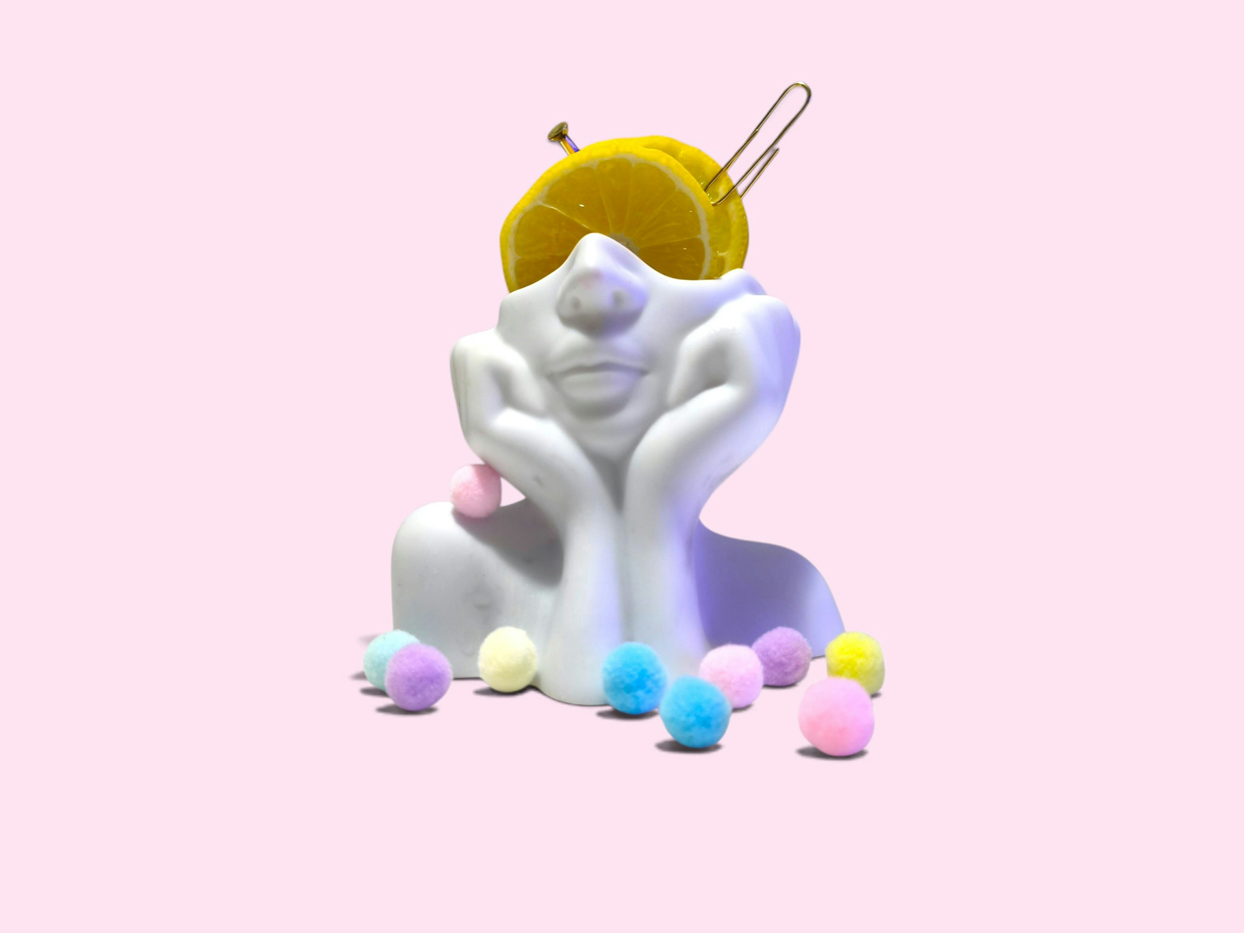 A white head sculpture with lemon slices, a pin, and paperclips on a pink background