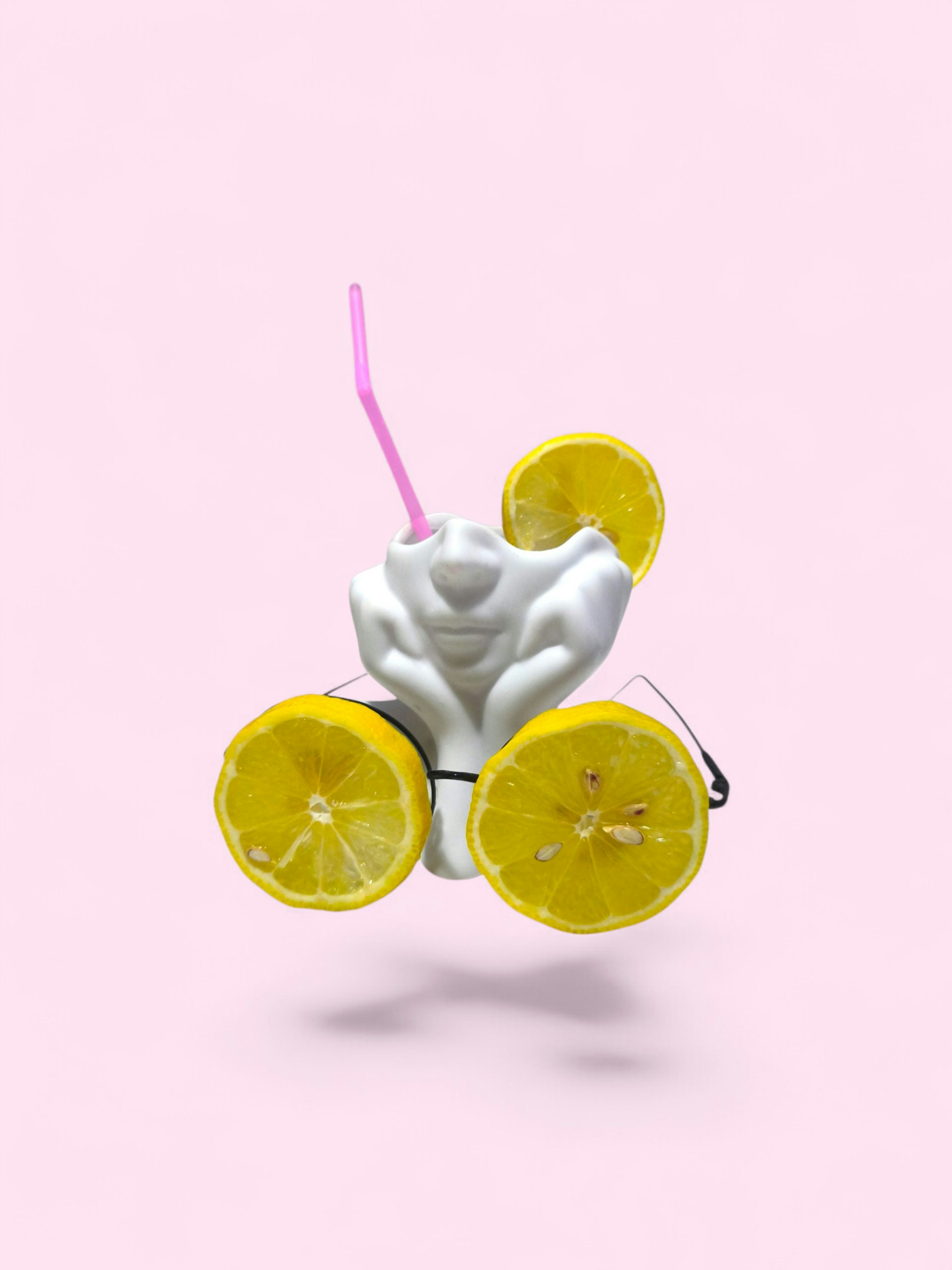 A white face-shaped mug wearing lemon slice glasses with a pink straw