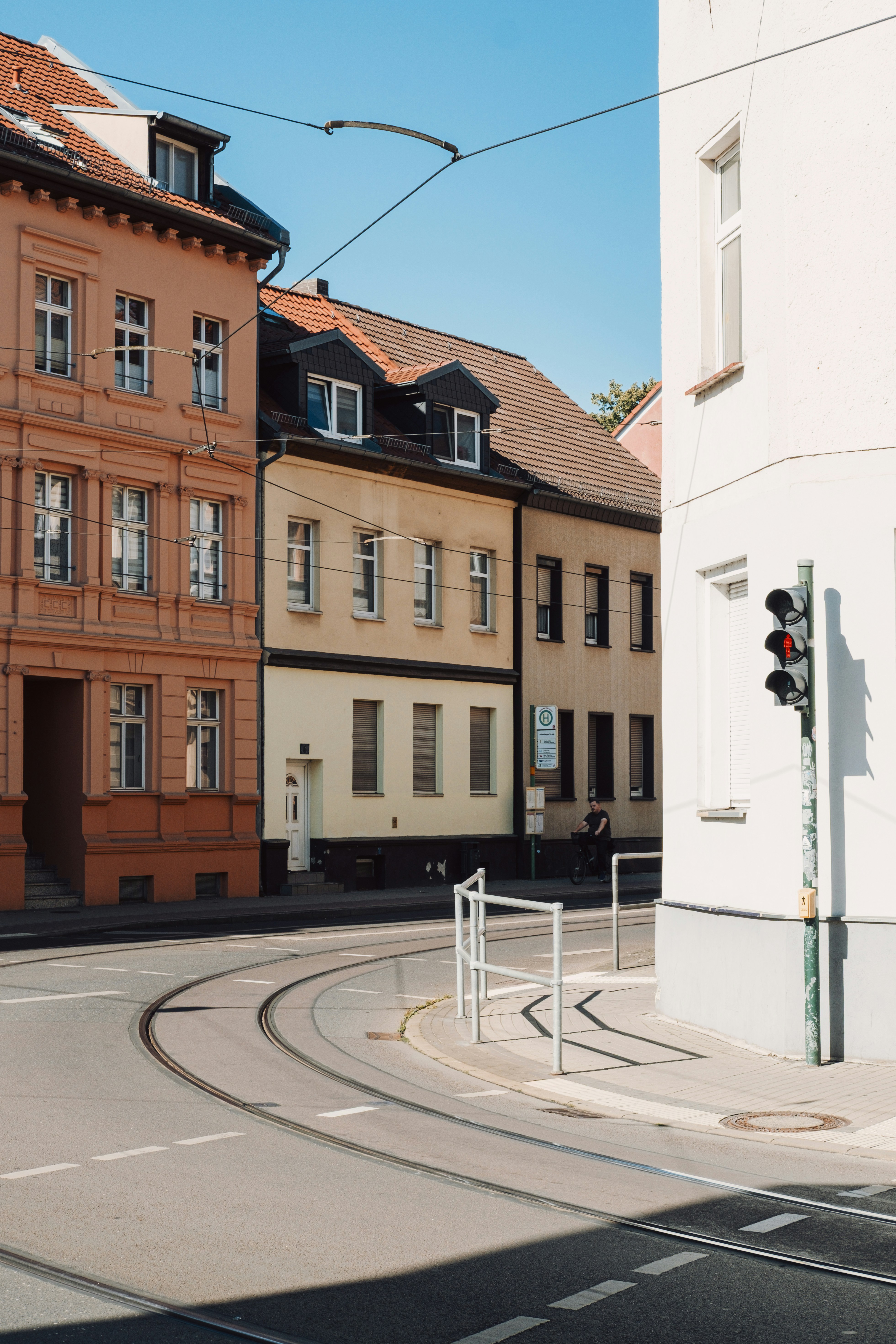 A person cycling past colorful buildings and tram tracks in Brandenburg, Germany.