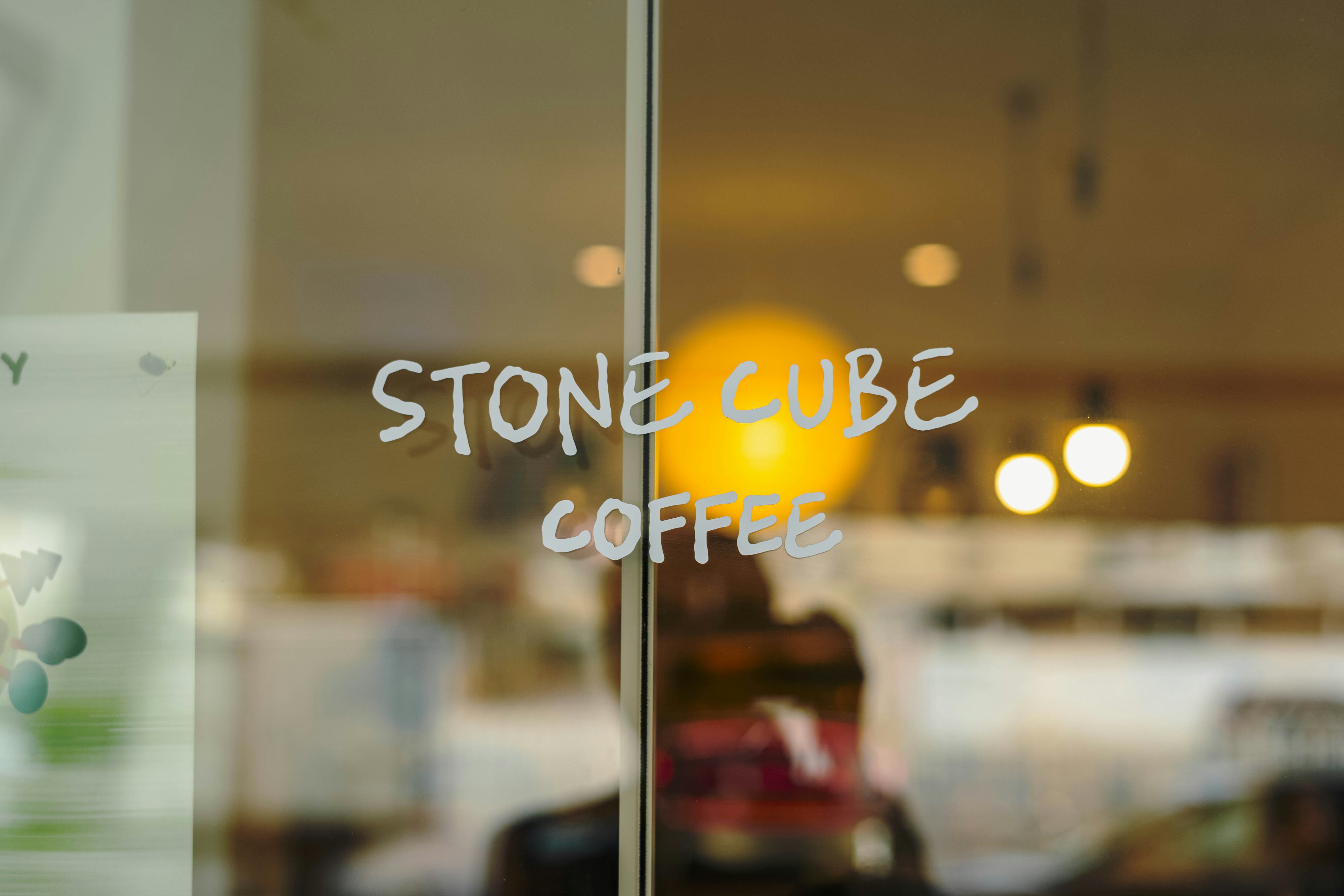 흰 글씨로 "STONE CUBE COFFEE"라고 적힌 유리문.
