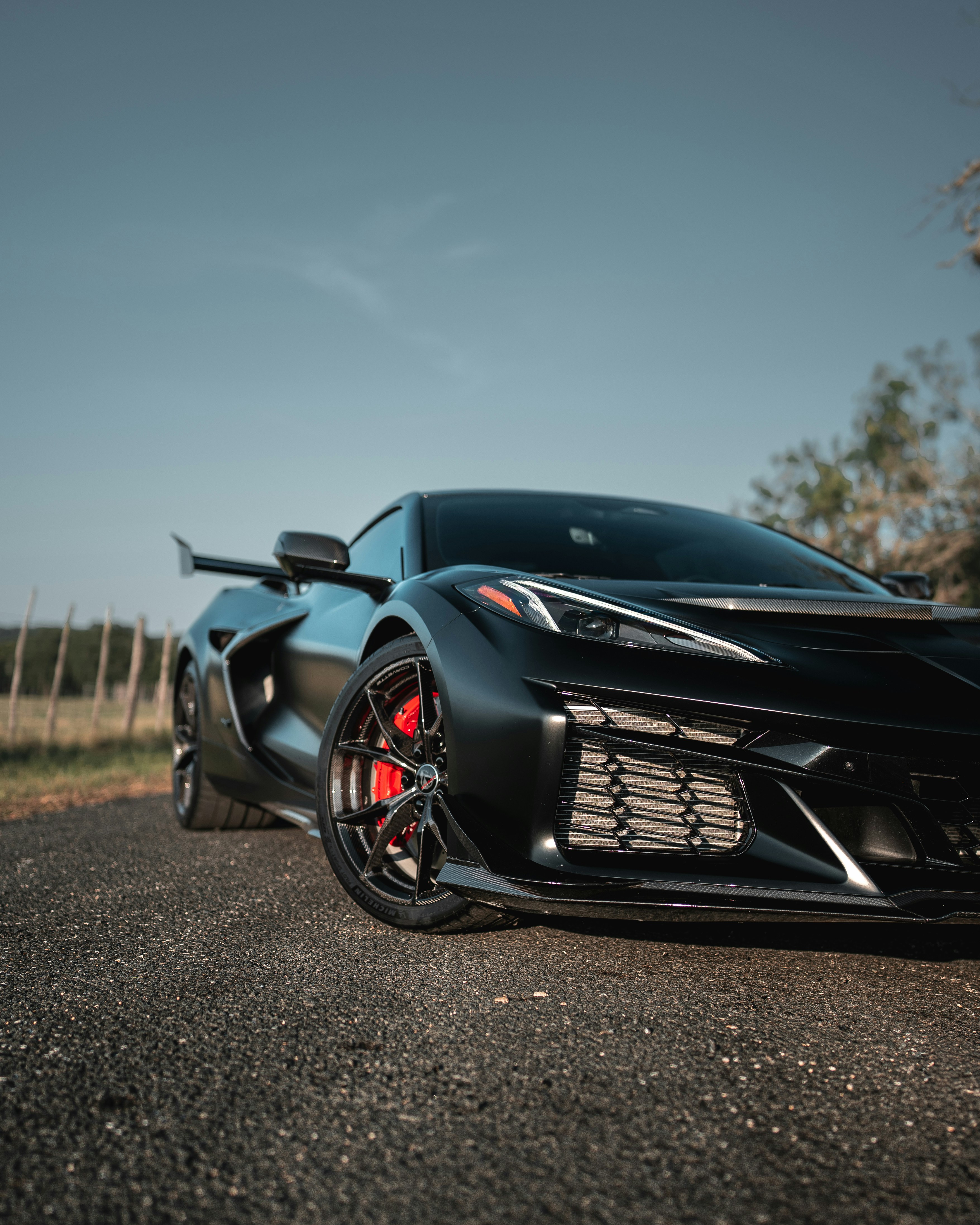A matte black sports car with red brake calipers on an asphalt road