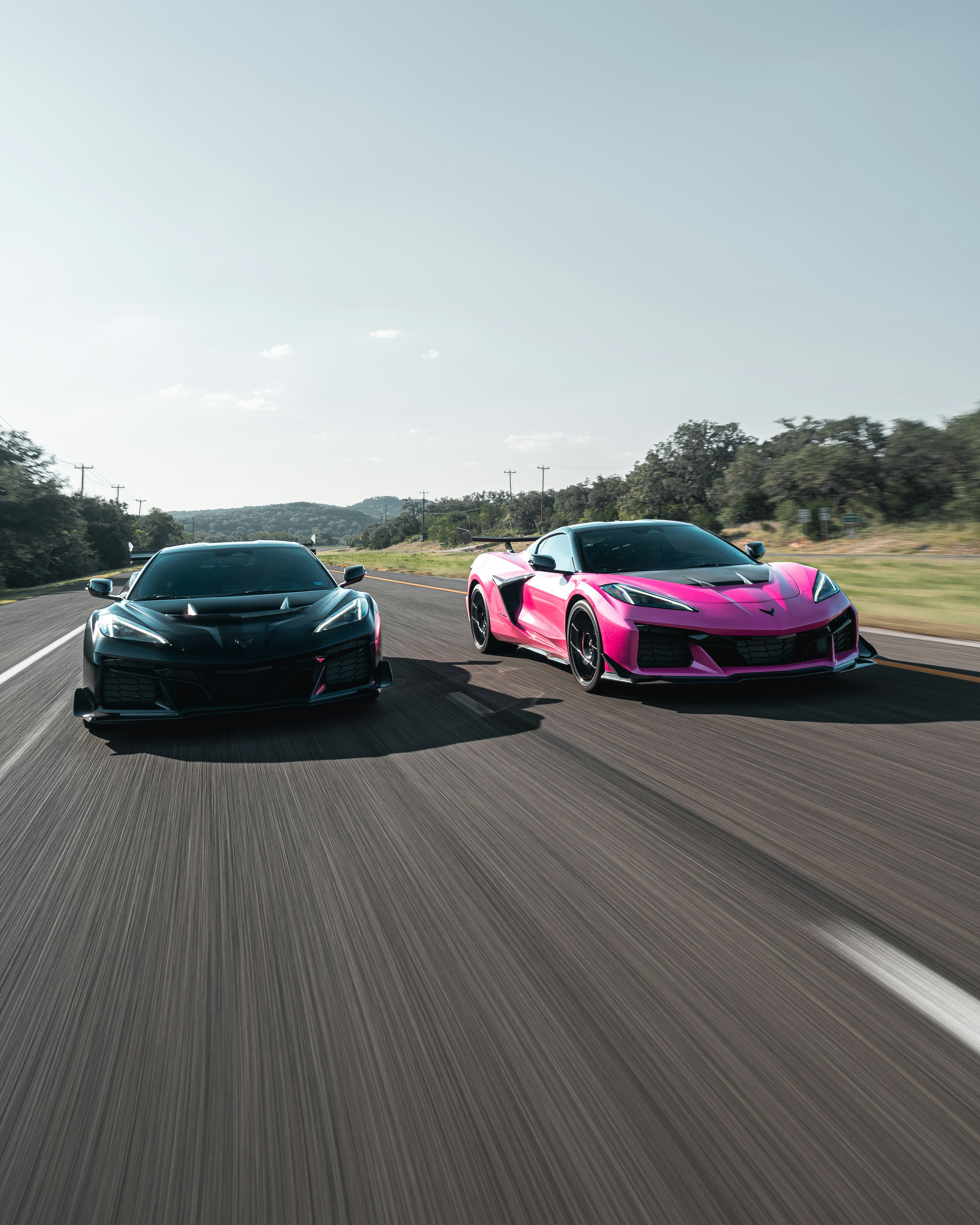 田舎道を走る黒とピンクのスポーツカー