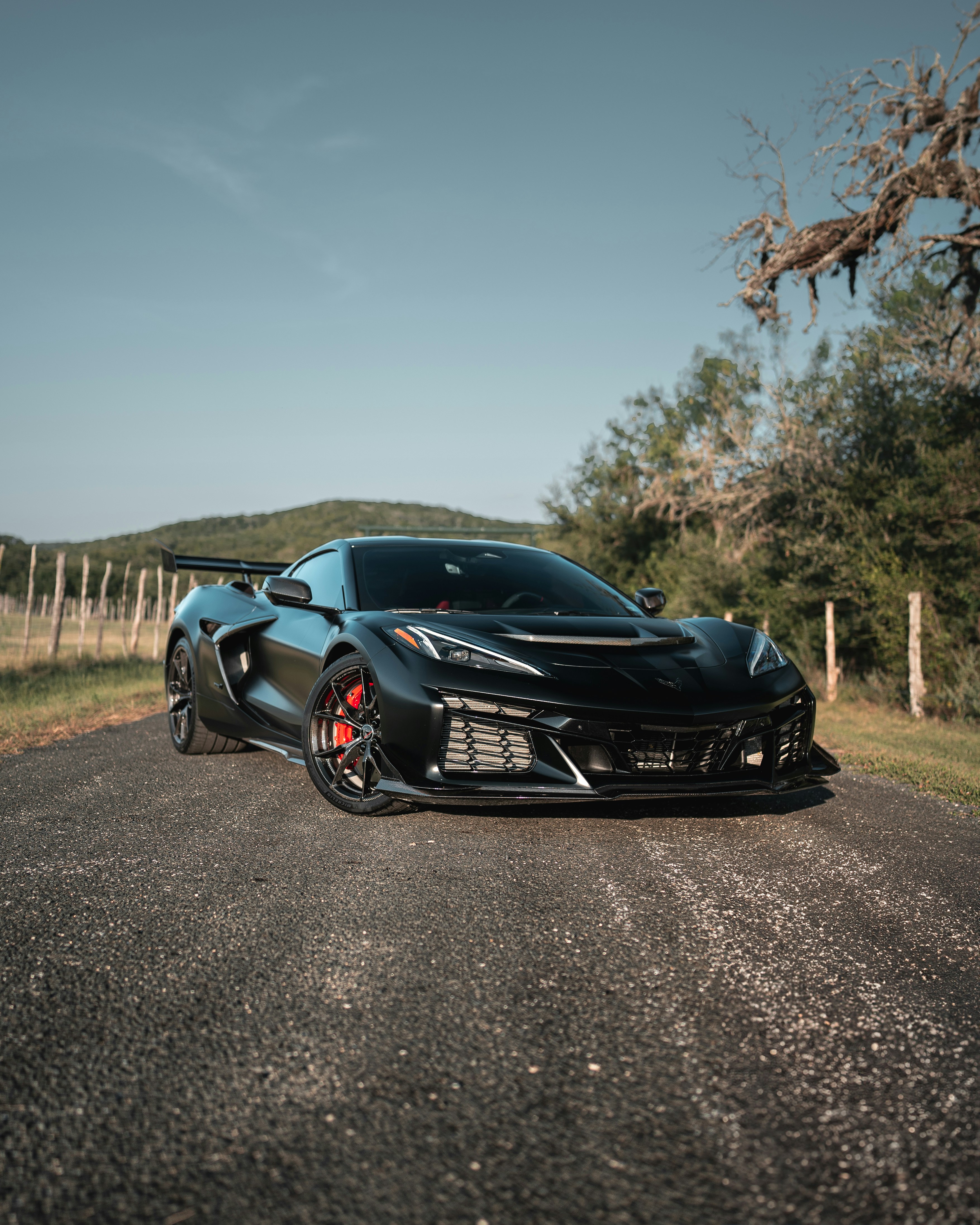 A black sports car with red brake calipers on a rural asphalt road
