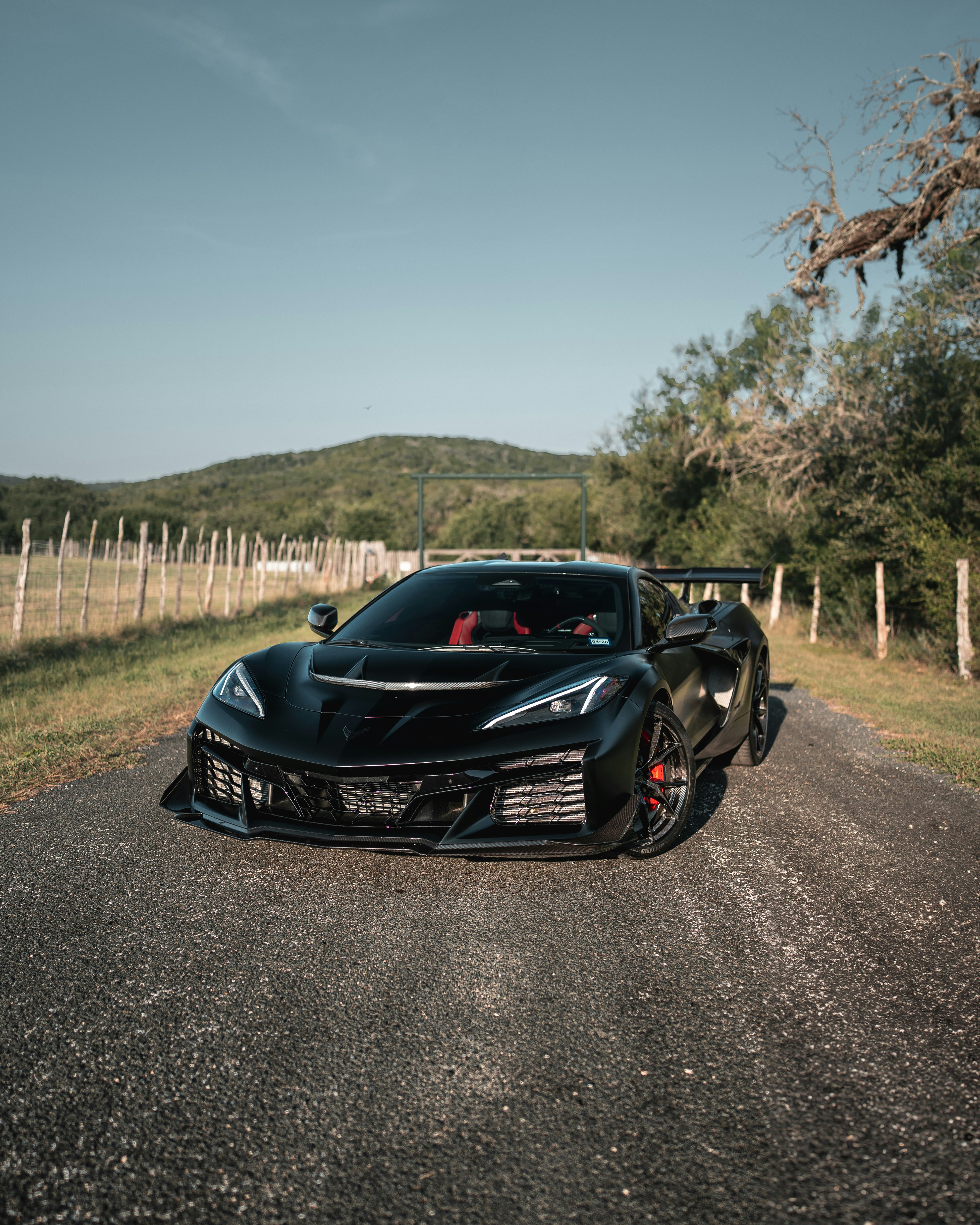 木製フェンスの近くの田舎道に停まっている黒いスポーツカー