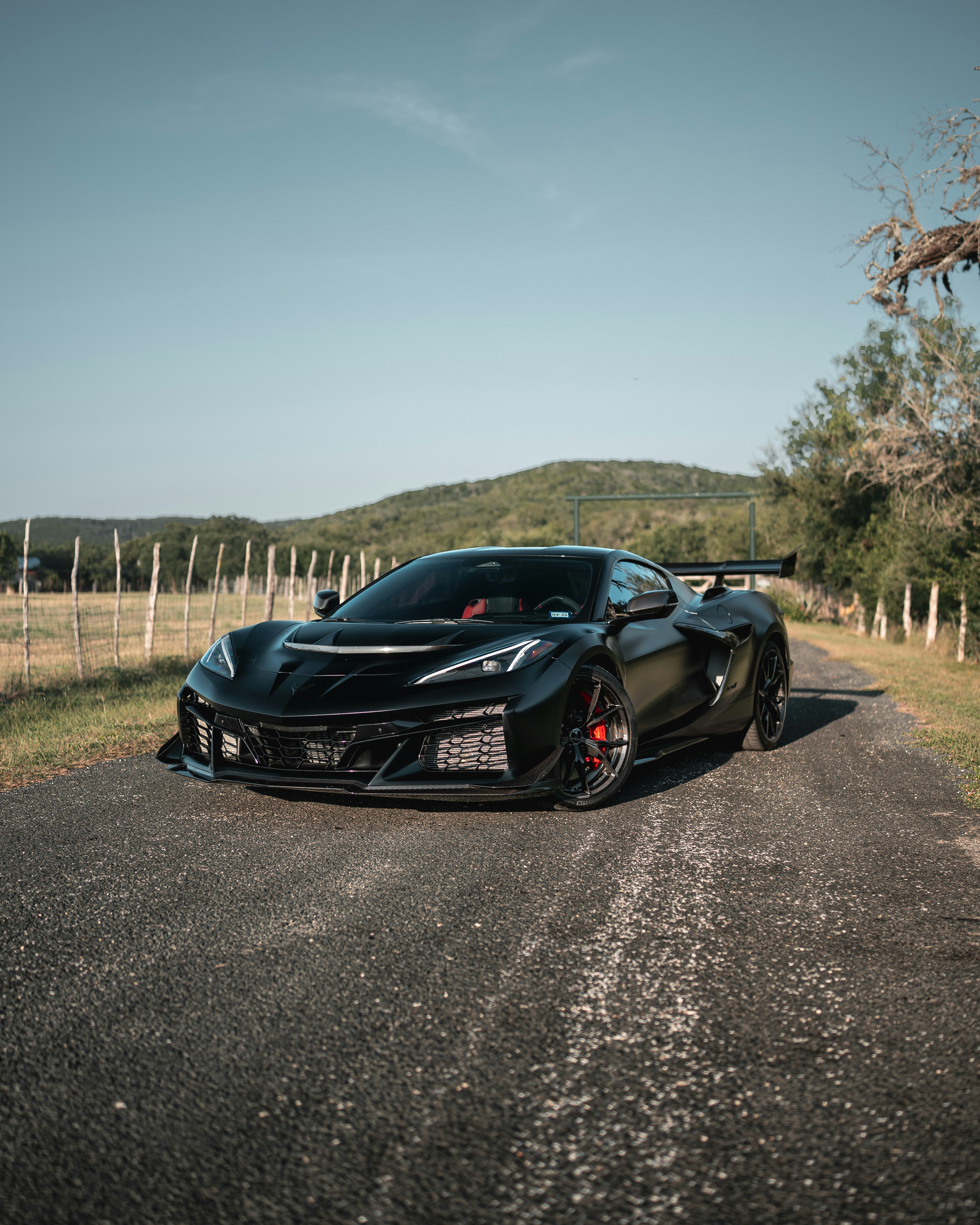 丘の近くの田舎道に停まっているマットな黒いスポーツカー
