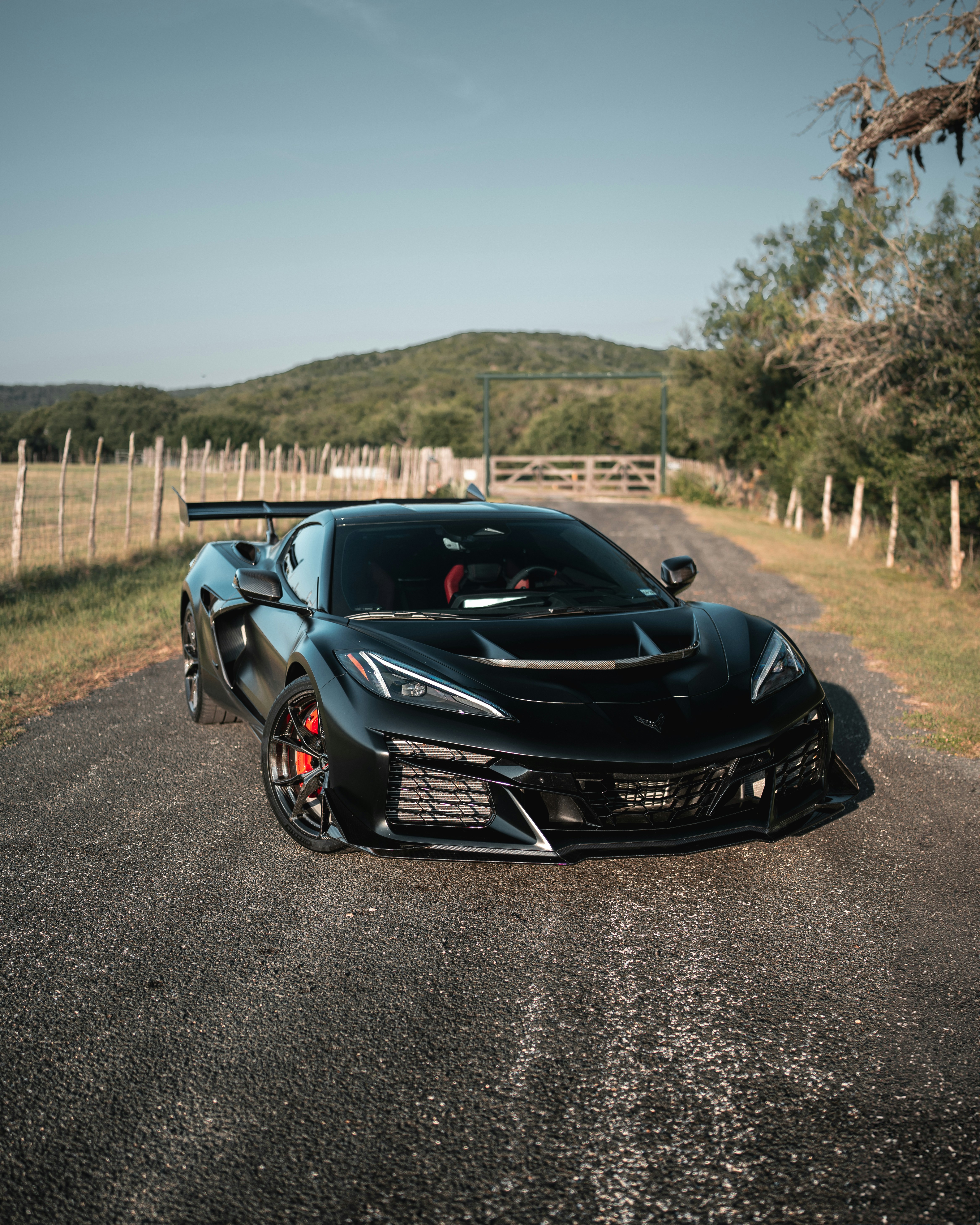 A black sports car with a rear wing on a rural asphalt road