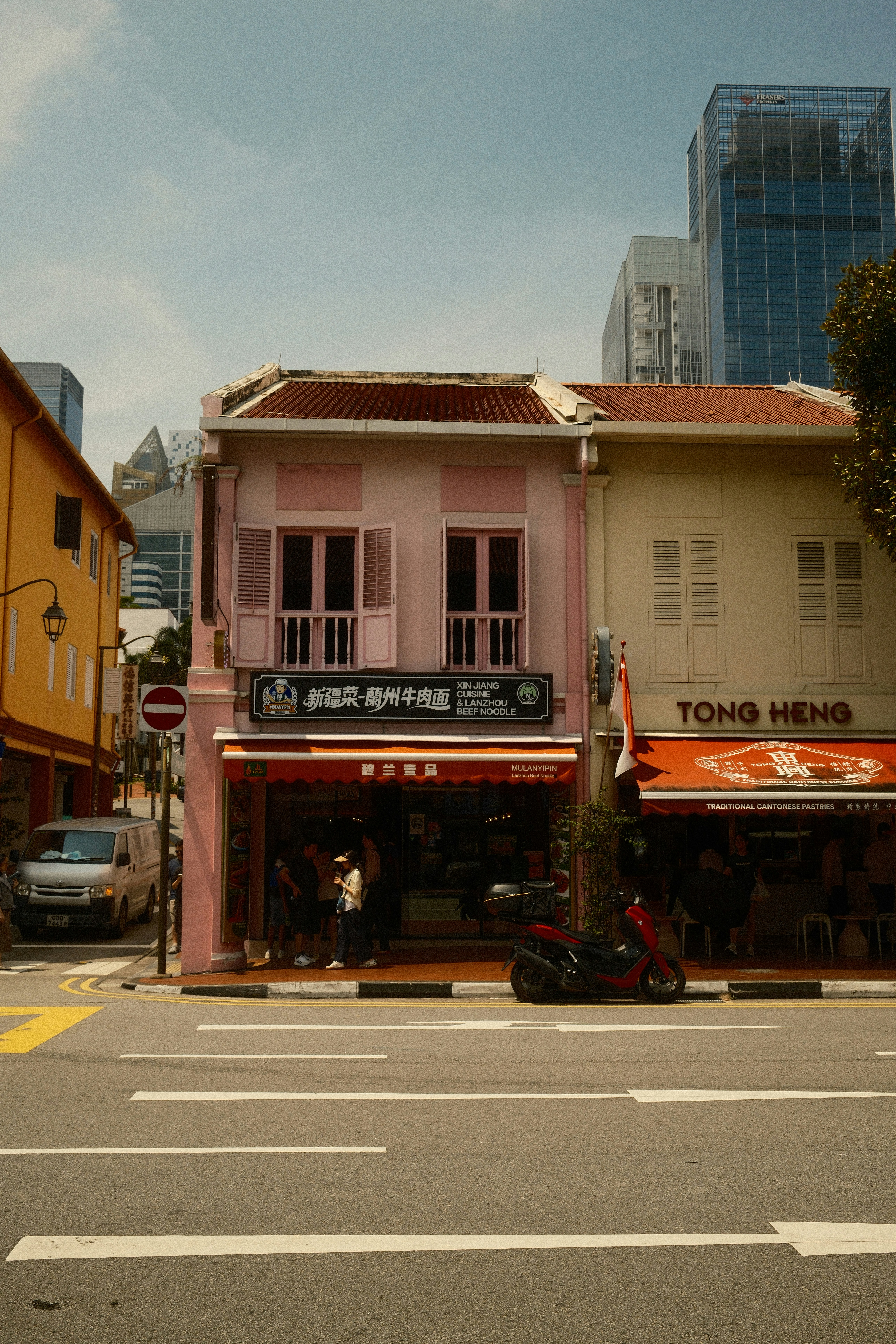 A pink shophouse with a noodle restaurant on a street in Singapore.
