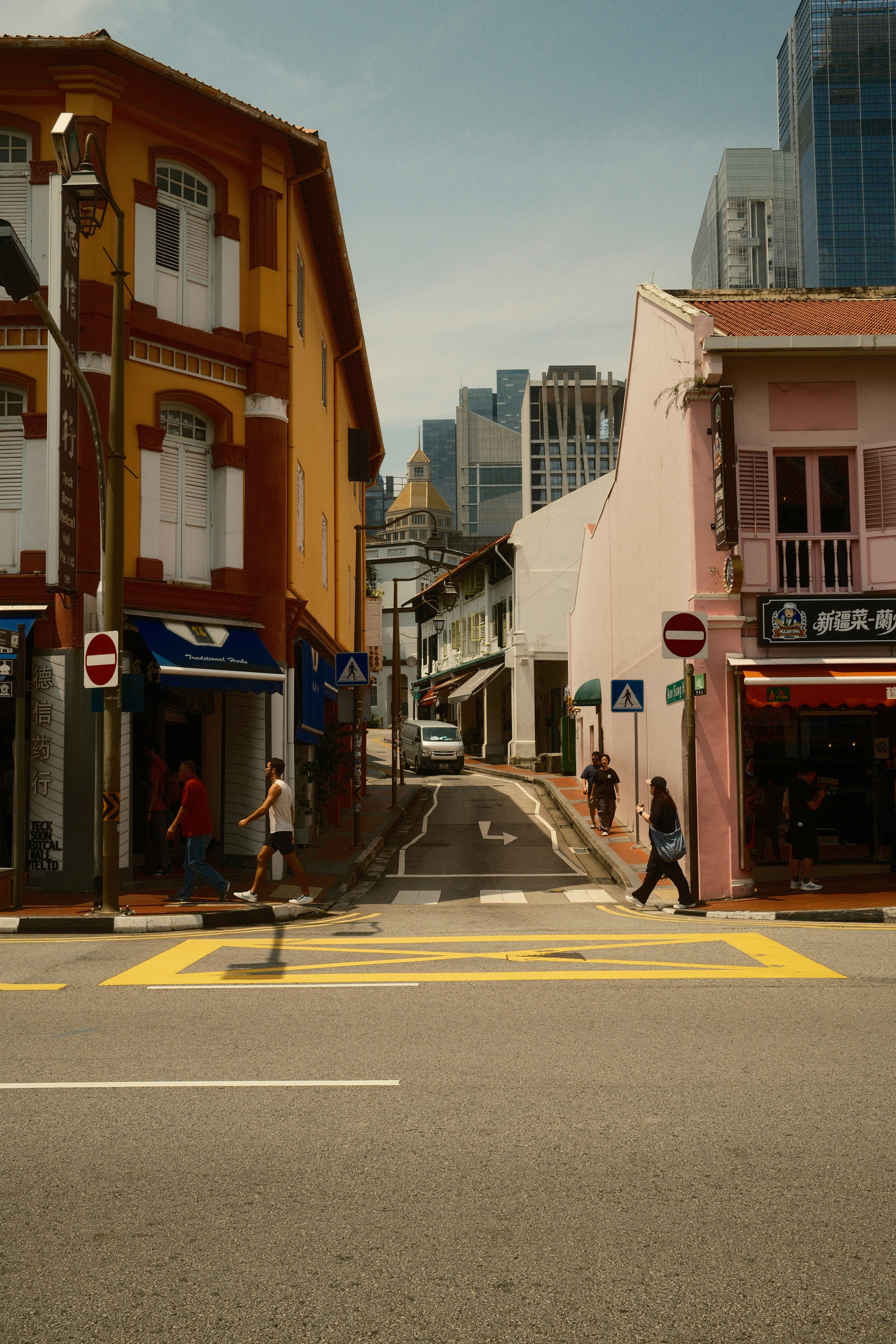 People walking on a street between colorful shophouses in Singapore.