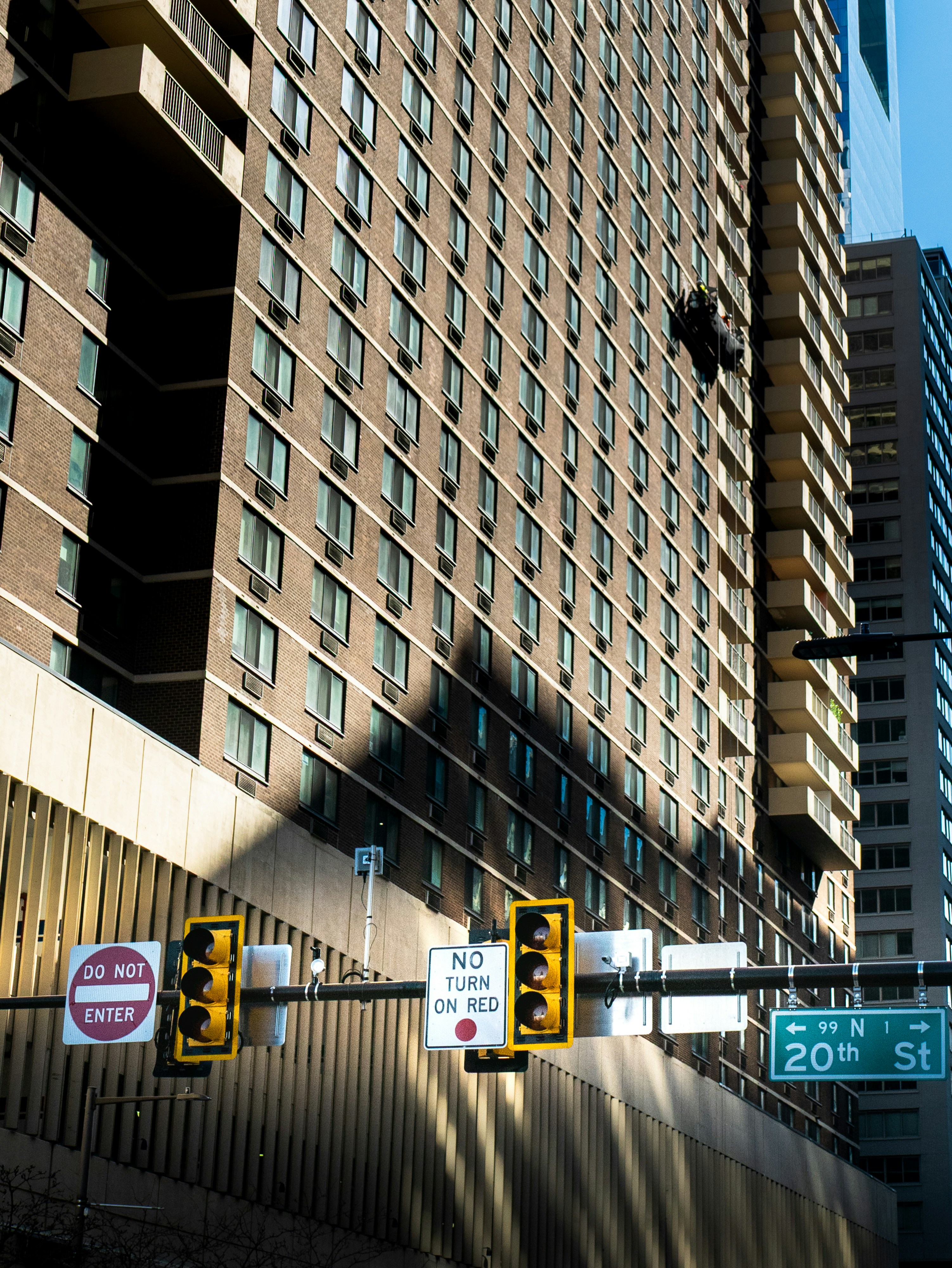 Traffic lights and street signs at an intersection below a tall apartment building